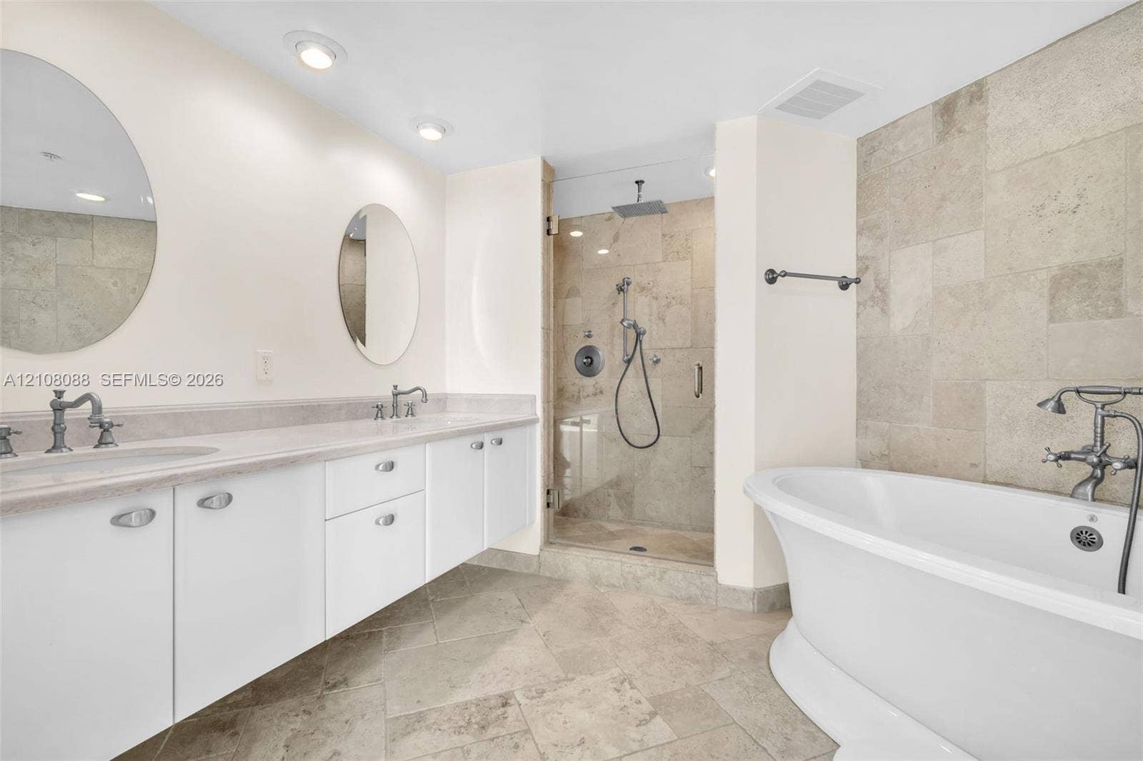 333 Las Olas Way, #2601, Fort Lauderdale, FL 33301 Bathroom featuring a double vanity with stone countertops, a freestanding soaking tub, a glass-enclosed shower with stone tile surround, and recessed lighting