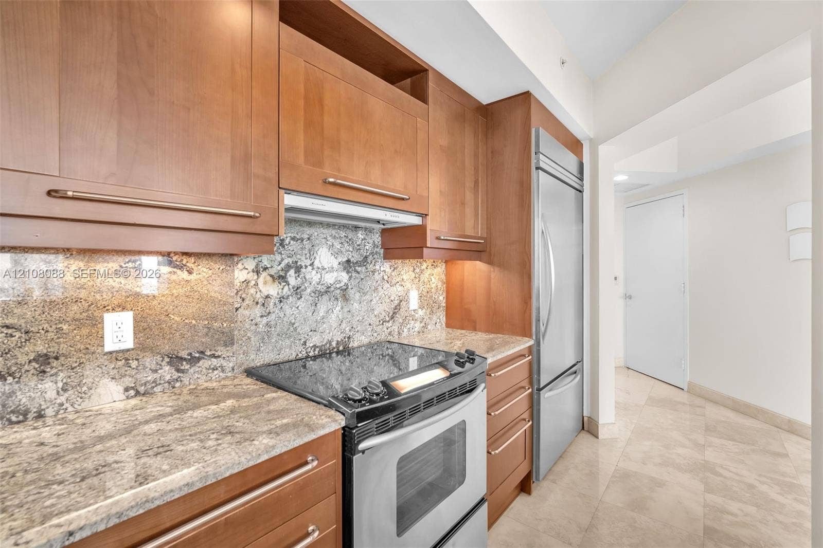 333 Las Olas Way, #2601, Fort Lauderdale, FL 33301 Kitchen featuring natural wood cabinetry, stone countertops, stone backsplash, stainless steel appliances, and stone flooring