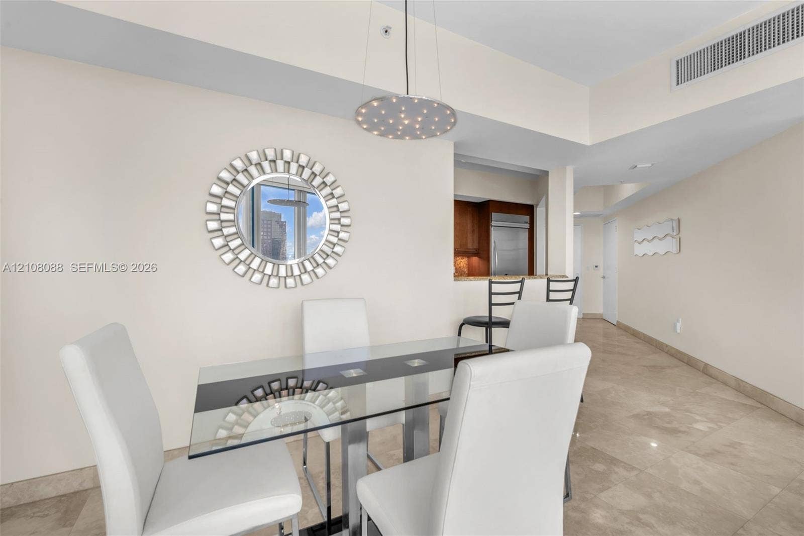 333 Las Olas Way, #2601, Fort Lauderdale, FL 33301 Polished stone tile flooring, circular decorative wall mirror, contemporary circular pendant light, and pass-through opening with stone-topped breakfast bar