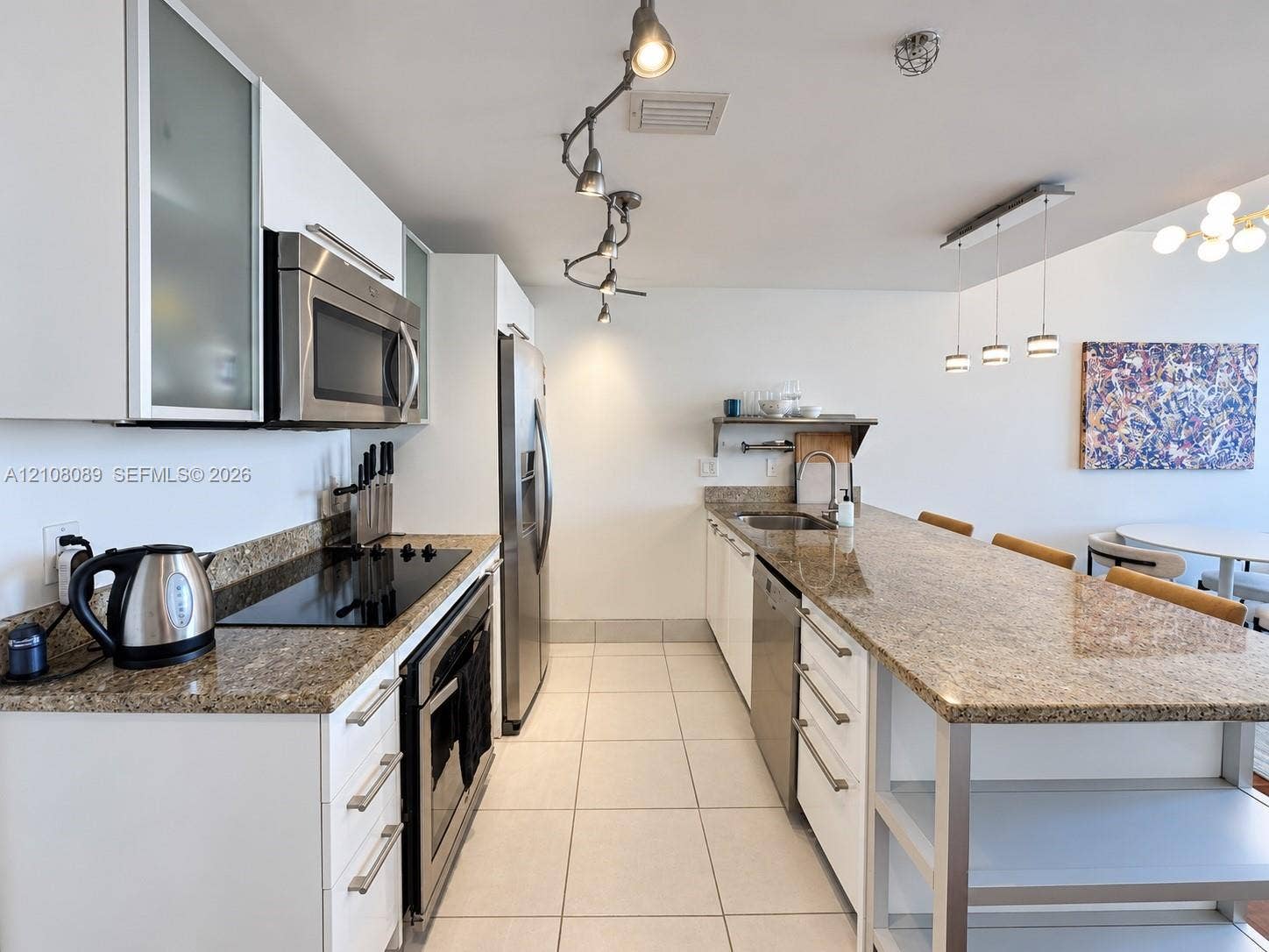185 SW 7th Street, #3608, Miami, FL 33130 Kitchen featuring white flat-panel cabinetry with frosted glass inserts, stone countertops, stainless steel appliances, tile flooring, and adjustable track lighting