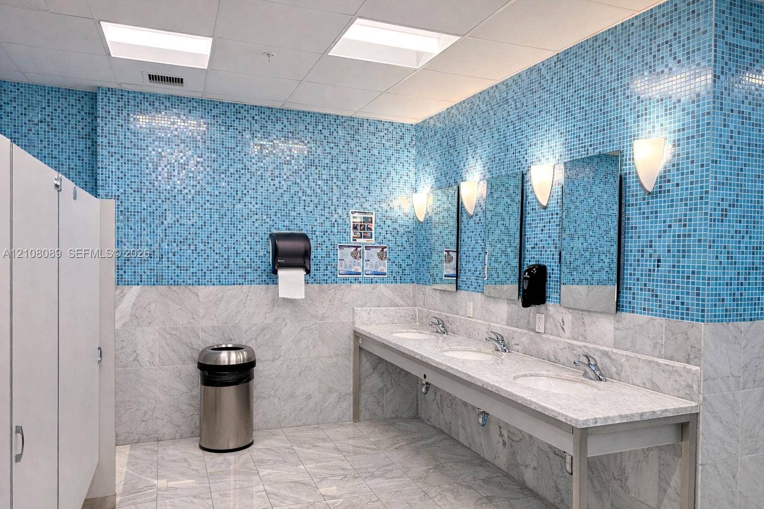 185 SW 7th Street, #3608, Miami, FL 33130 Multi-station stone vanity with integrated sinks, polished stone flooring, blue mosaic tile wall accents, and wall-mounted sconce lighting