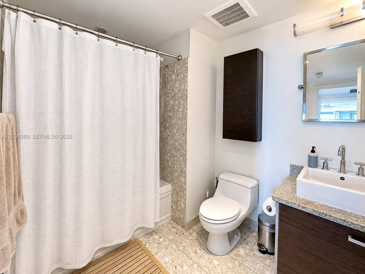 185 SW 7th Street, #3608, Miami, FL 33130 Bathroom featuring a vessel sink with a chrome faucet, stone-composite countertop, dark wood-finish cabinetry, wall-mounted storage cabinet, and mosaic tile surround