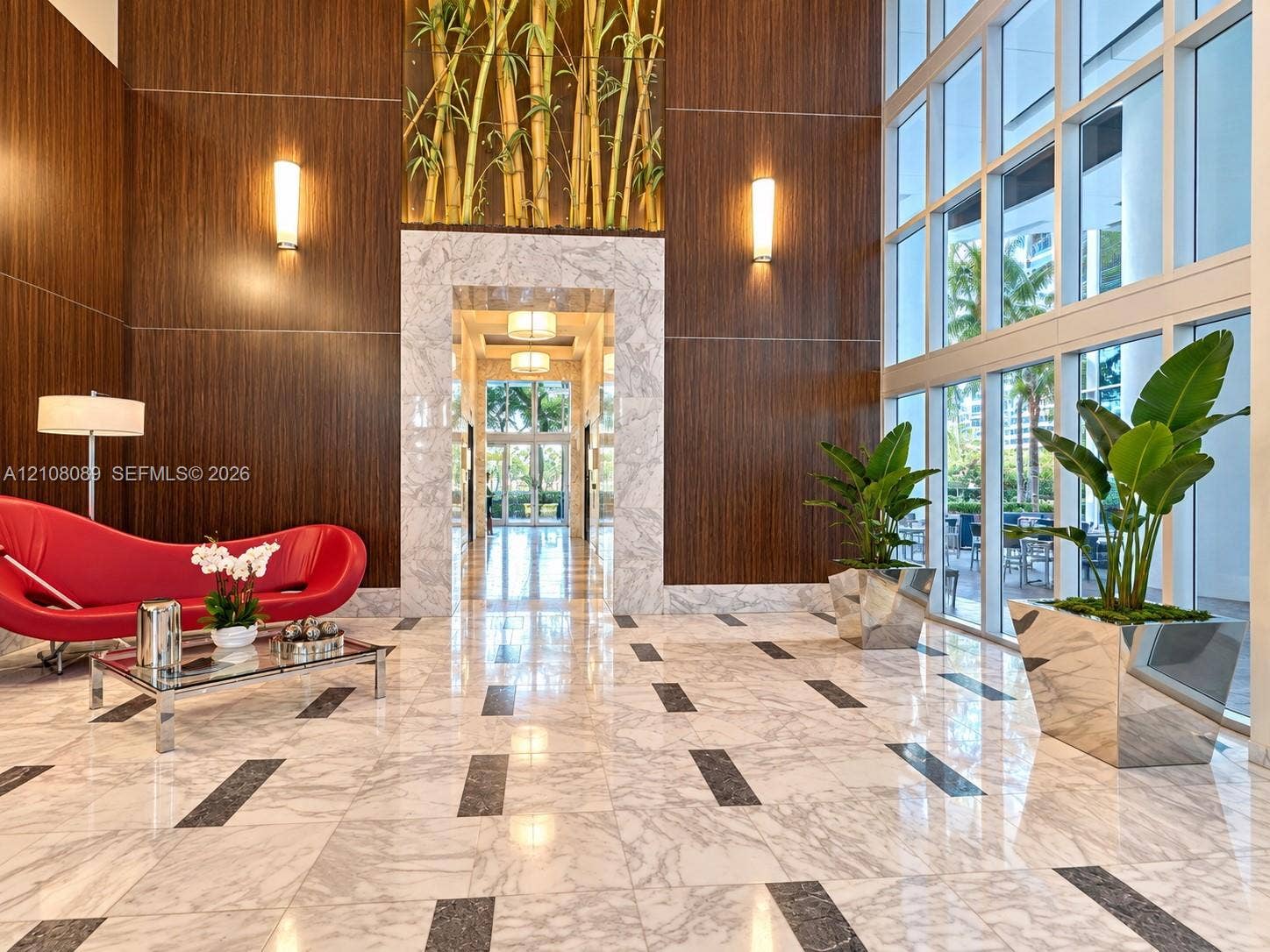 185 SW 7th Street, #3608, Miami, FL 33130 Lobby featuring floor-to-ceiling windows, polished stone flooring with decorative inlay, wood-paneled walls, stone-trimmed entryway, and integrated wall-mounted lighting