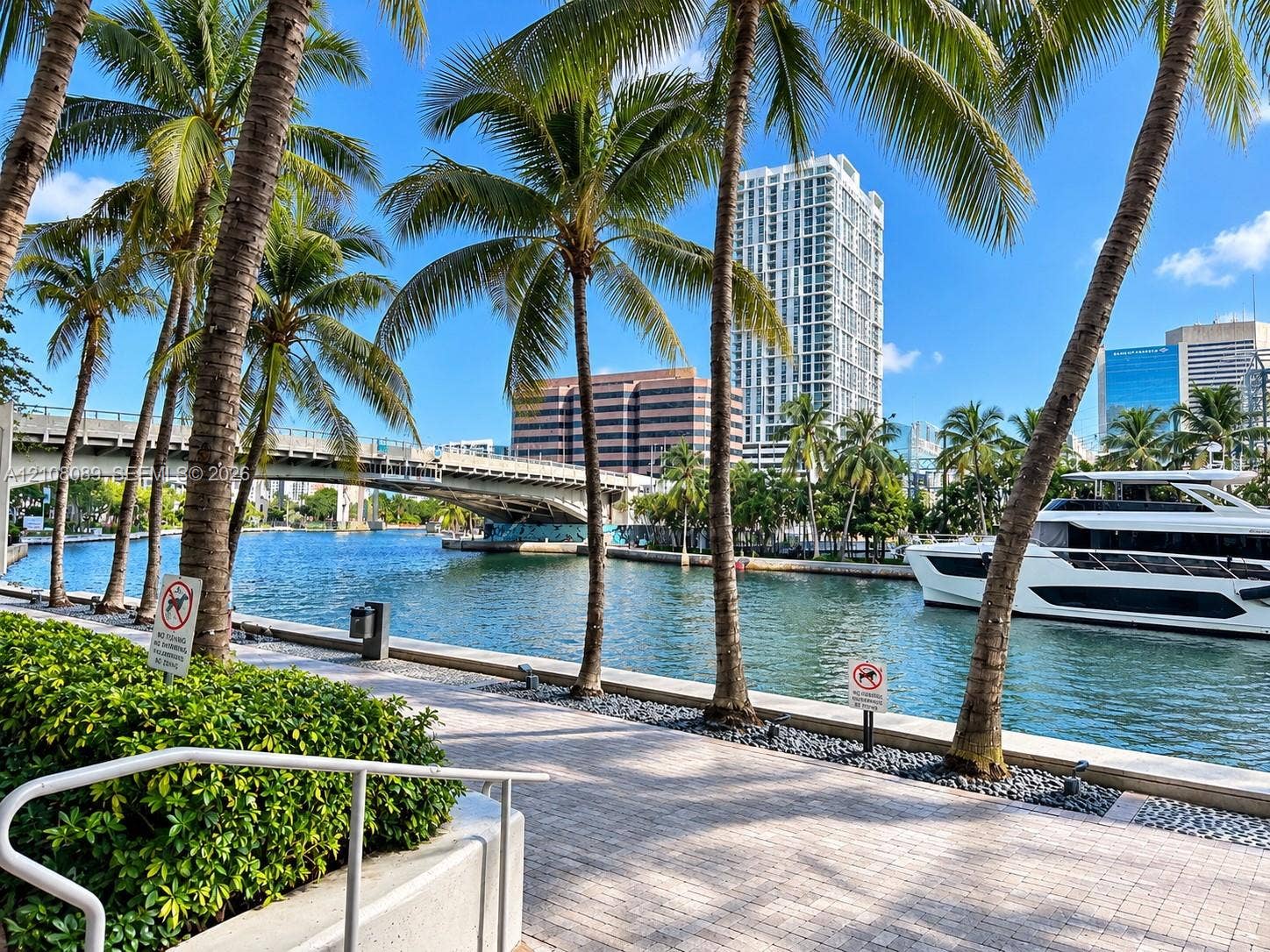 185 SW 7th Street, #3608, Miami, FL 33130 Waterfront promenade featuring stone paver walkways, mature palm trees, and bulkhead retaining walls along a waterway