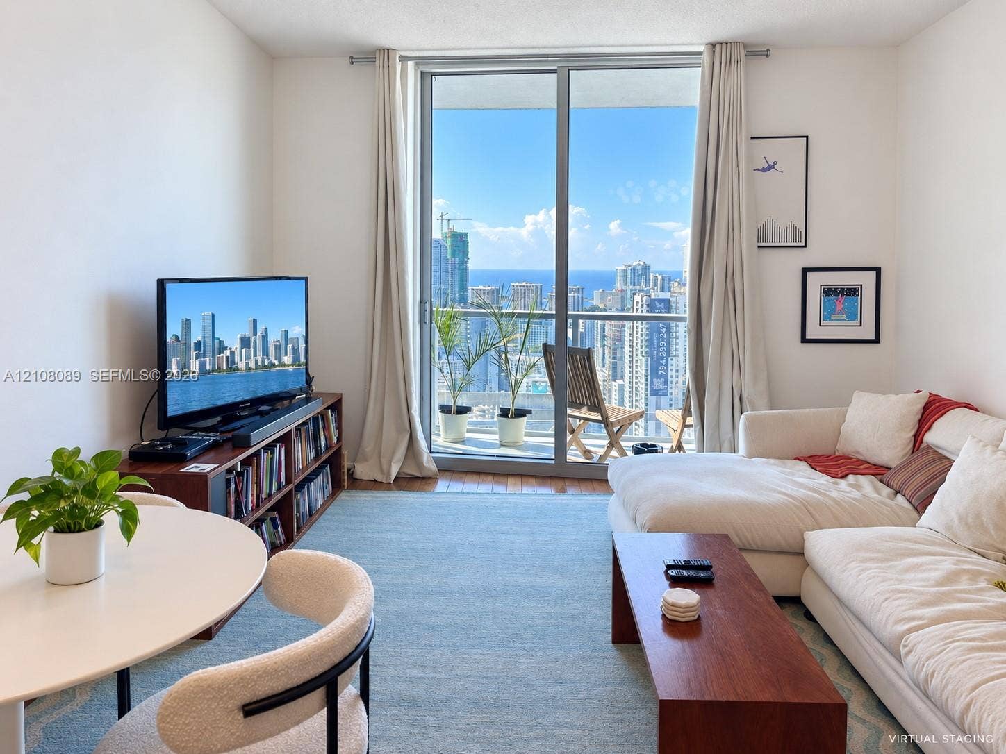185 SW 7th Street, #3608, Miami, FL 33130 Living area featuring floor-to-ceiling glass sliding doors, balcony access, and expansive urban and water scenery