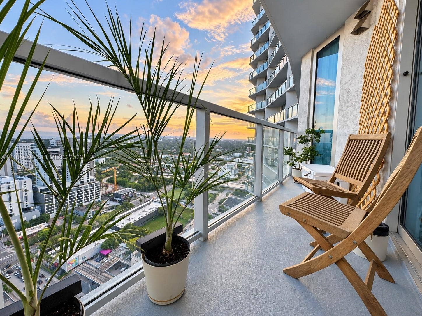 185 SW 7th Street, #3608, Miami, FL 33130 Covered balcony featuring glass railing, metal framework, and concrete flooring with sunset horizon backdrop