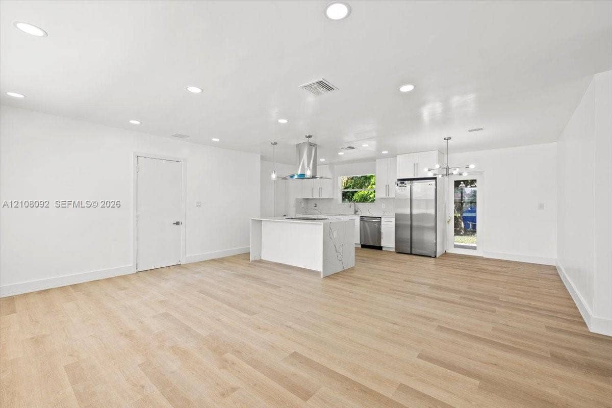 Bright room featuring wood-finish flooring, dual windows, and an integrated ceiling fan with light fixture