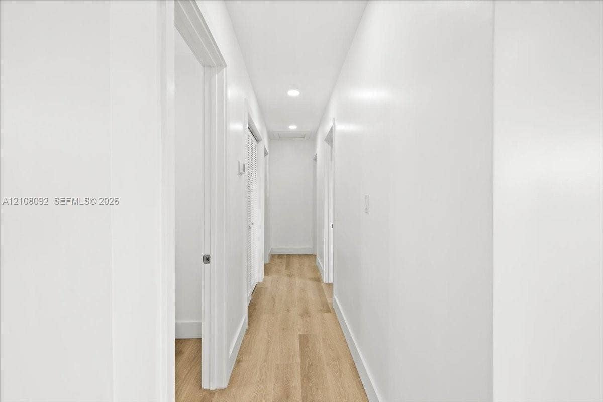 Interior space featuring wood-finish flooring, a neutral color palette, a central ceiling fan with integrated lighting, and a single-pane window