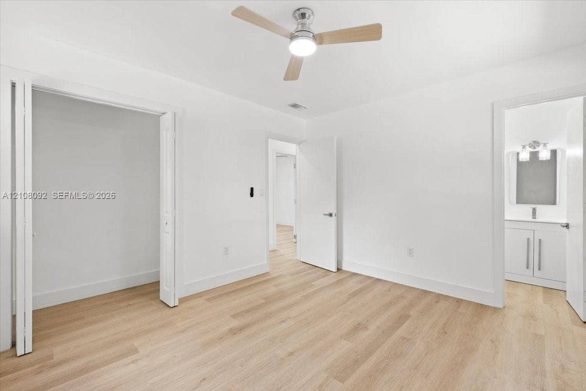 Neutral-toned interior featuring wood-finish flooring, a contemporary three-blade ceiling fan with integrated lighting, bi-fold closet doors, and solid-core interior doors
