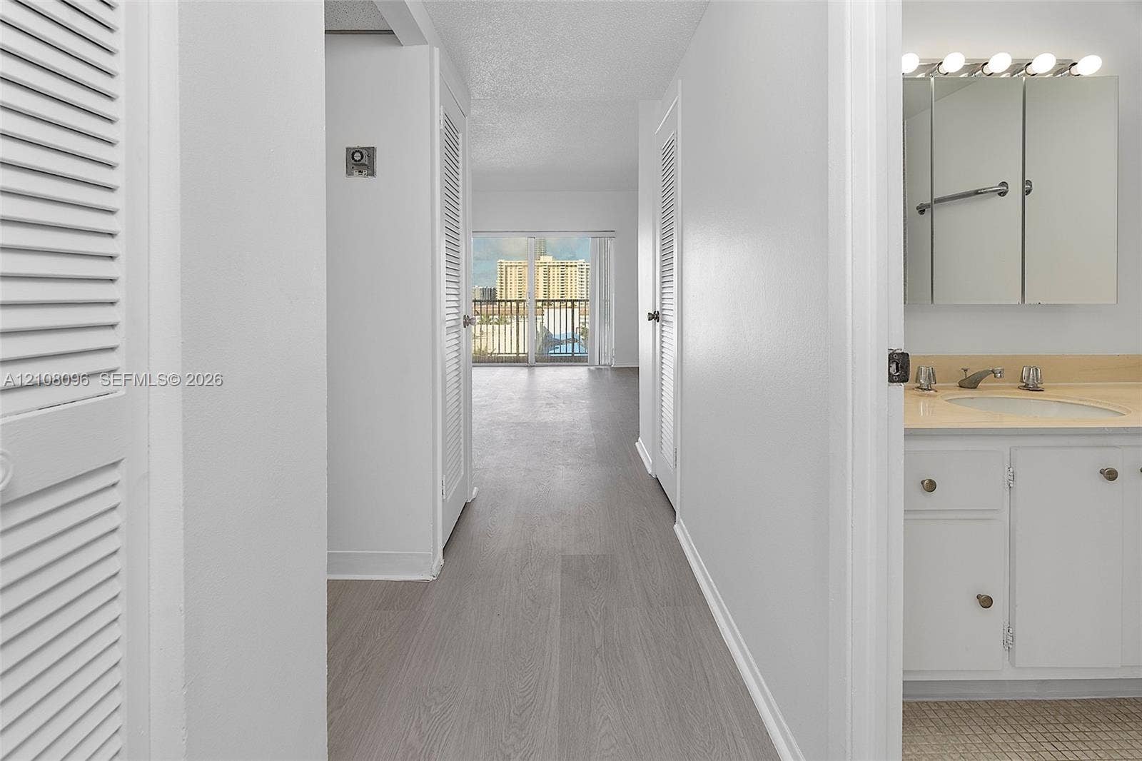 1965 S Ocean Drive, #6H, Hallandale Beach, Hallandale Beach, FL 33009 Hallway featuring wood-finish flooring, louvered closet doors, and sliding glass doors leading to a balcony