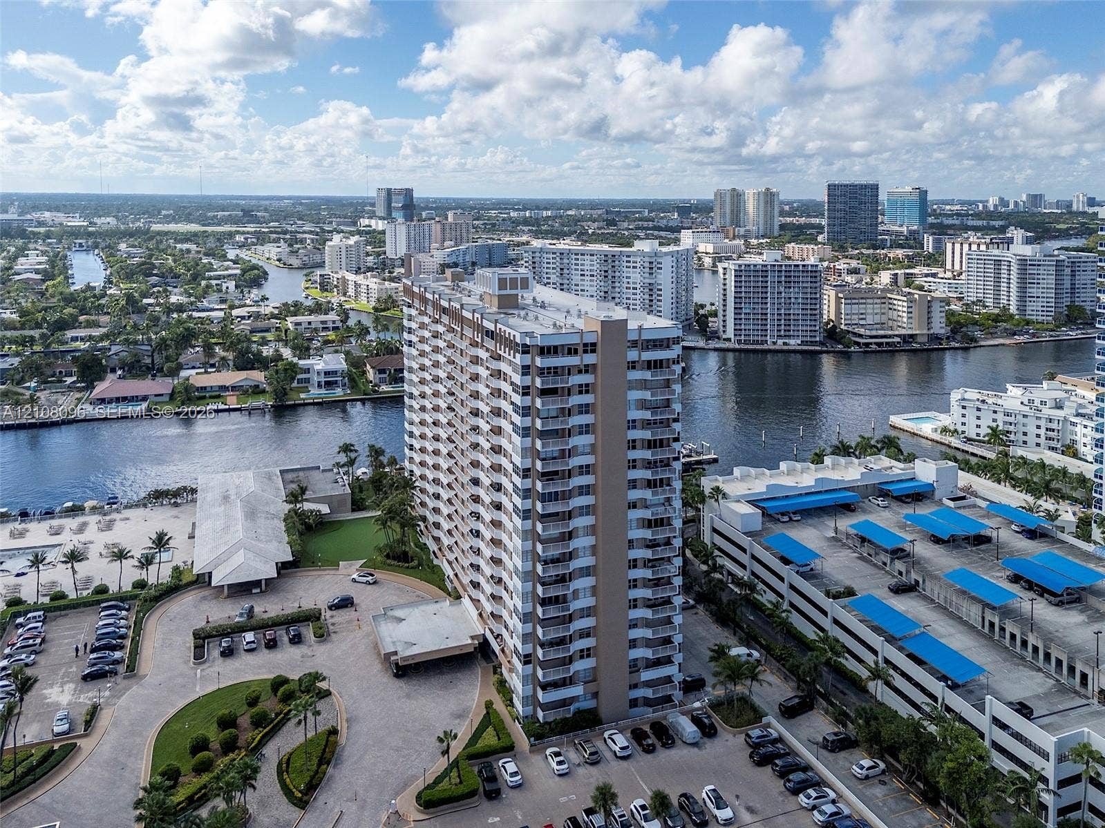 1965 S Ocean Drive, #6H, Hallandale Beach, Hallandale Beach, FL 33009 High-rise residential building featuring stacked private balconies, an attached multi-level parking structure, a paved motor court, and waterfront positioning