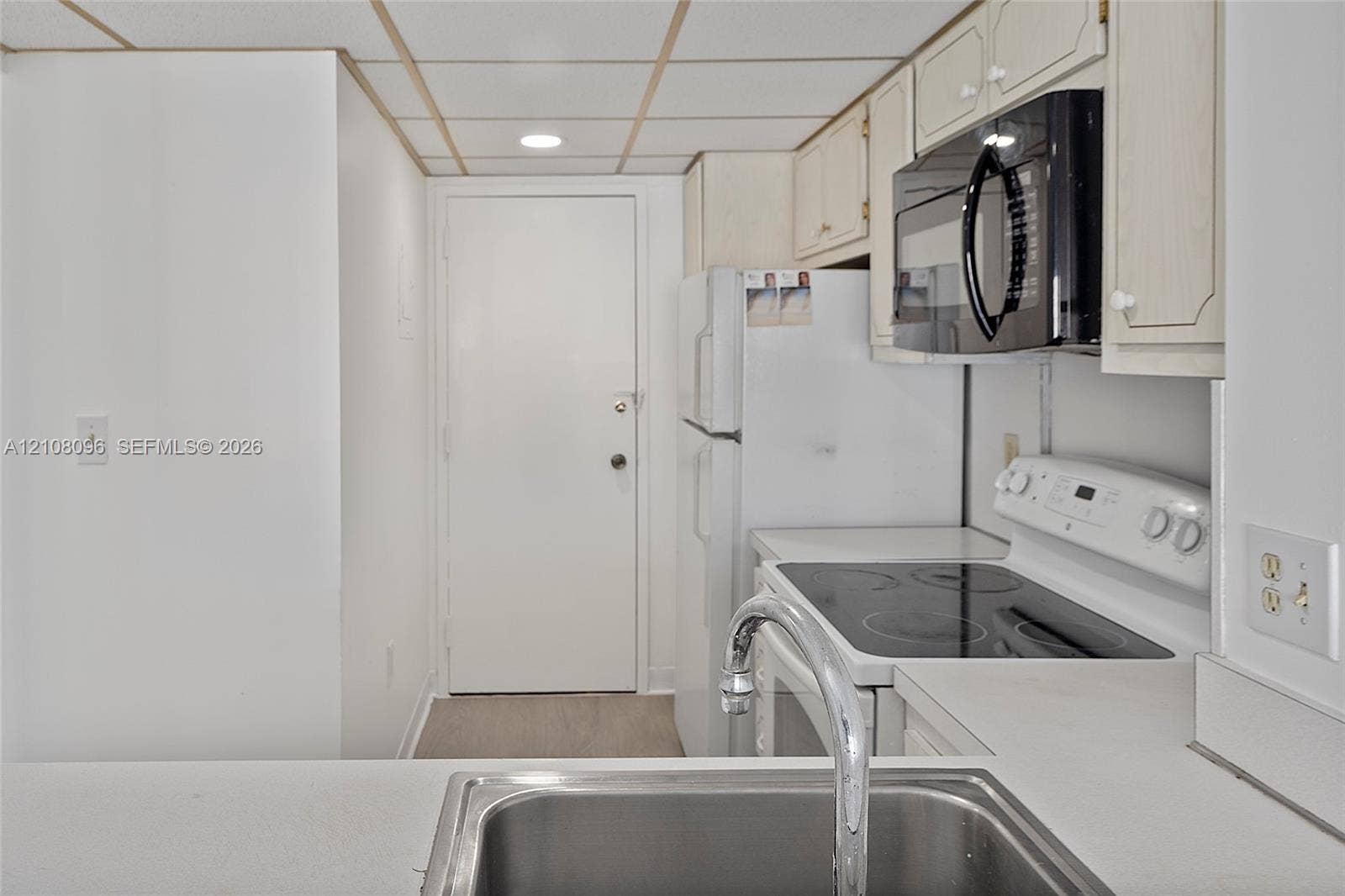 1965 S Ocean Drive, #6H, Hallandale Beach, Hallandale Beach, FL 33009 Kitchen featuring white cabinetry, an integrated microwave, a built-in electric range, and a stainless steel sink with a chrome faucet