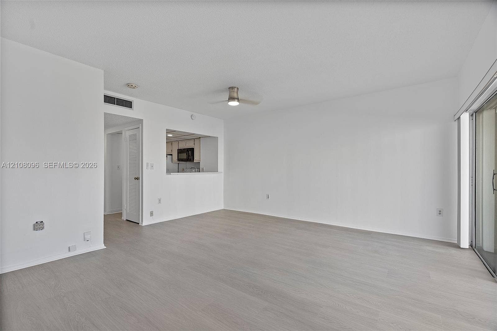 1965 S Ocean Drive, #6H, Hallandale Beach, Hallandale Beach, FL 33009 Open-concept interior featuring neutral wall tones, wood-finish flooring, a ceiling fan, and sliding glass doors
