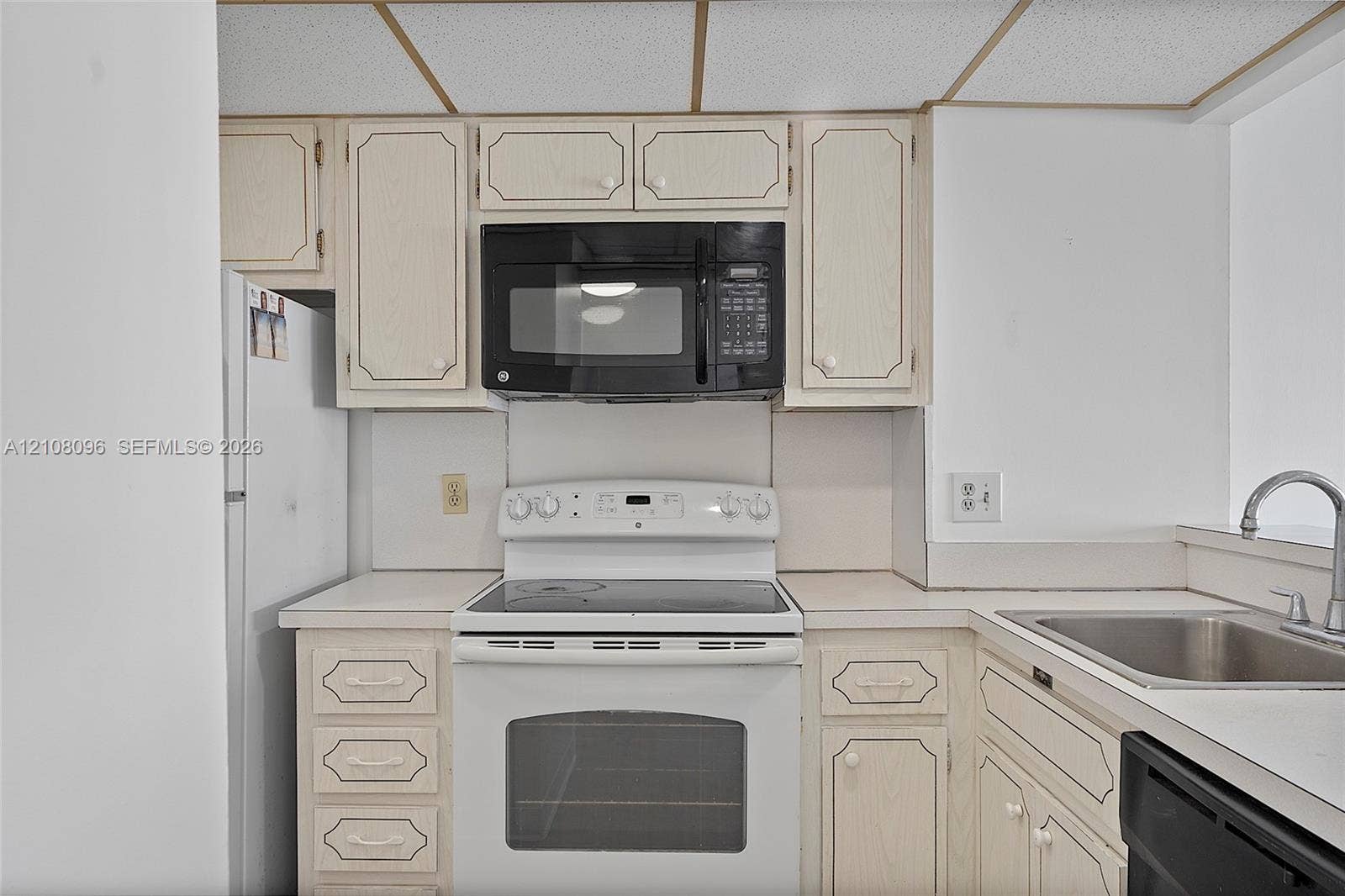 1965 S Ocean Drive, #6H, Hallandale Beach, Hallandale Beach, FL 33009 Kitchen featuring neutral-toned cabinetry, a built-in black microwave, a white electric range, a stainless steel sink with a chrome faucet, and integrated appliance placement
