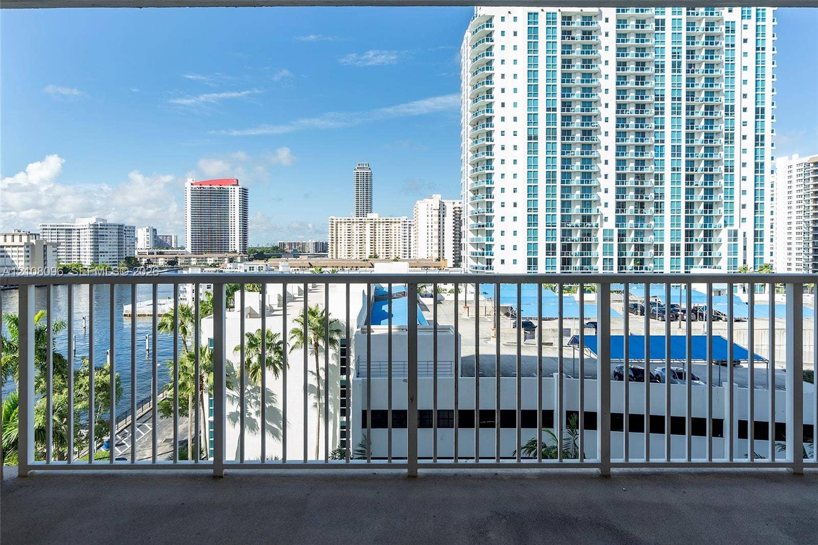 1965 S Ocean Drive, #6H, Hallandale Beach, Hallandale Beach, FL 33009 Covered balcony featuring white vertical railings and concrete flooring with urban, waterway, and palm tree scenery