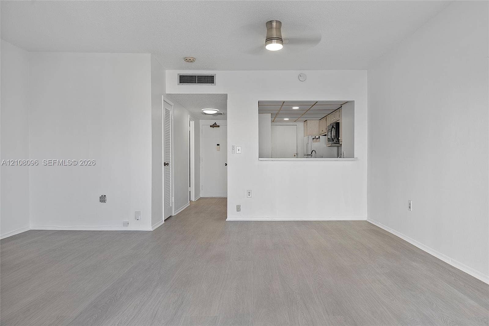 1965 S Ocean Drive, #6H, Hallandale Beach, Hallandale Beach, FL 33009 Open-concept interior featuring light wood-finish flooring, a pass-through opening to the kitchen, and a ceiling-mounted light fixture