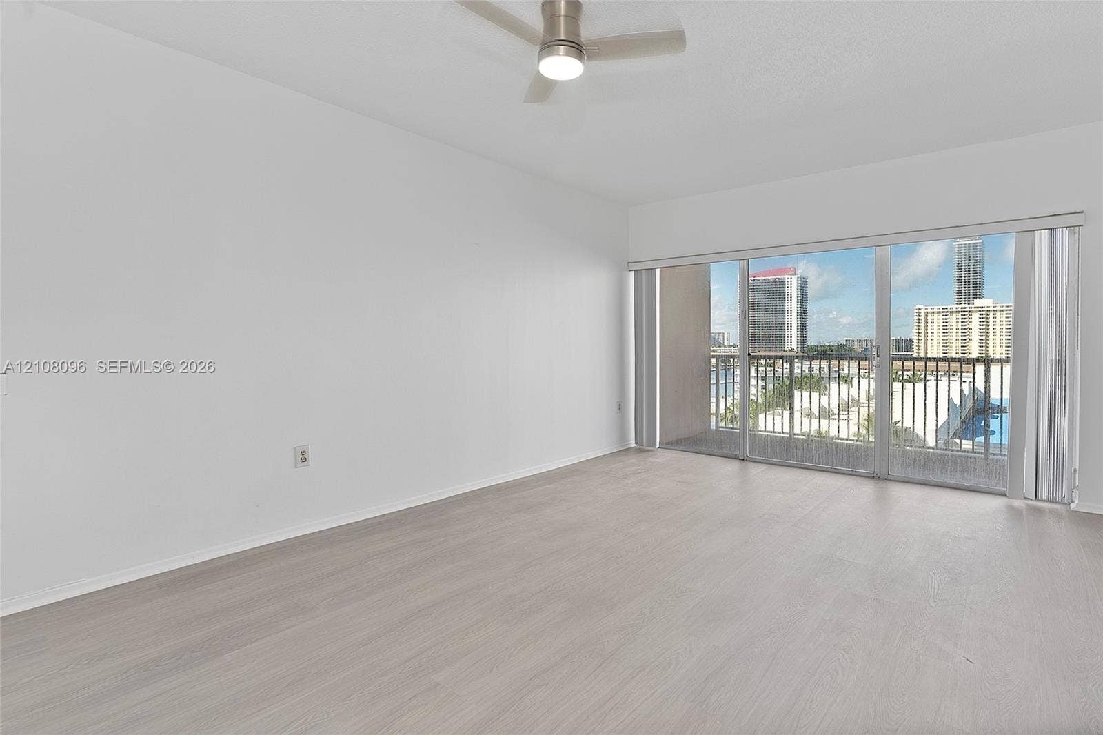 1965 S Ocean Drive, #6H, Hallandale Beach, Hallandale Beach, FL 33009 Neutral-toned wood-finish flooring, ceiling-mounted fan with integrated lighting, and full-height sliding glass doors opening to a private balcony