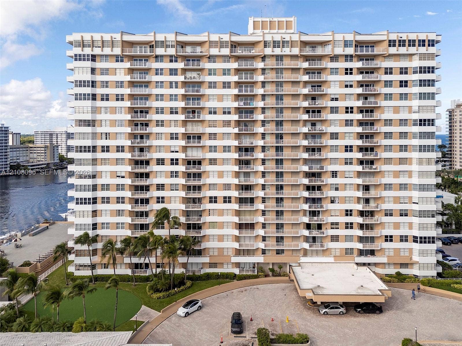 1965 S Ocean Drive, #6H, Hallandale Beach, Hallandale Beach, FL 33009 High-rise residential building featuring stacked private balconies, a covered porte-cochre, paved motor court, and landscaped grounds with mature palm trees