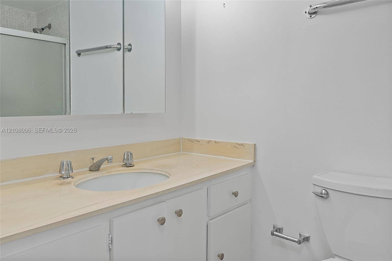 1965 S Ocean Drive, #6H, Hallandale Beach, Hallandale Beach, FL 33009 Bathroom featuring a light-toned solid surface vanity countertop, integrated sink, white cabinetry with metal hardware, wall-mounted medicine cabinet, and a framed glass shower enclosure