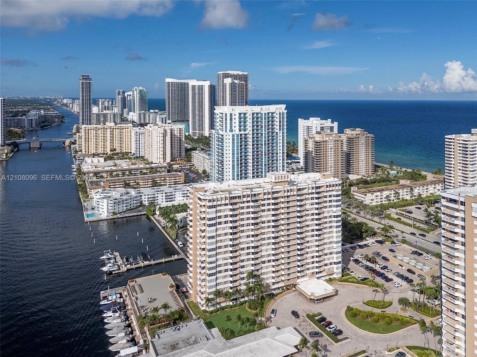 1965 S Ocean Drive, #6H, Hallandale Beach, Hallandale Beach, FL 33009 Aerial perspective of a multi-story residential building featuring integrated boat docking facilities, waterfront positioning, proximity to the coastline, and expansive paved parking areas