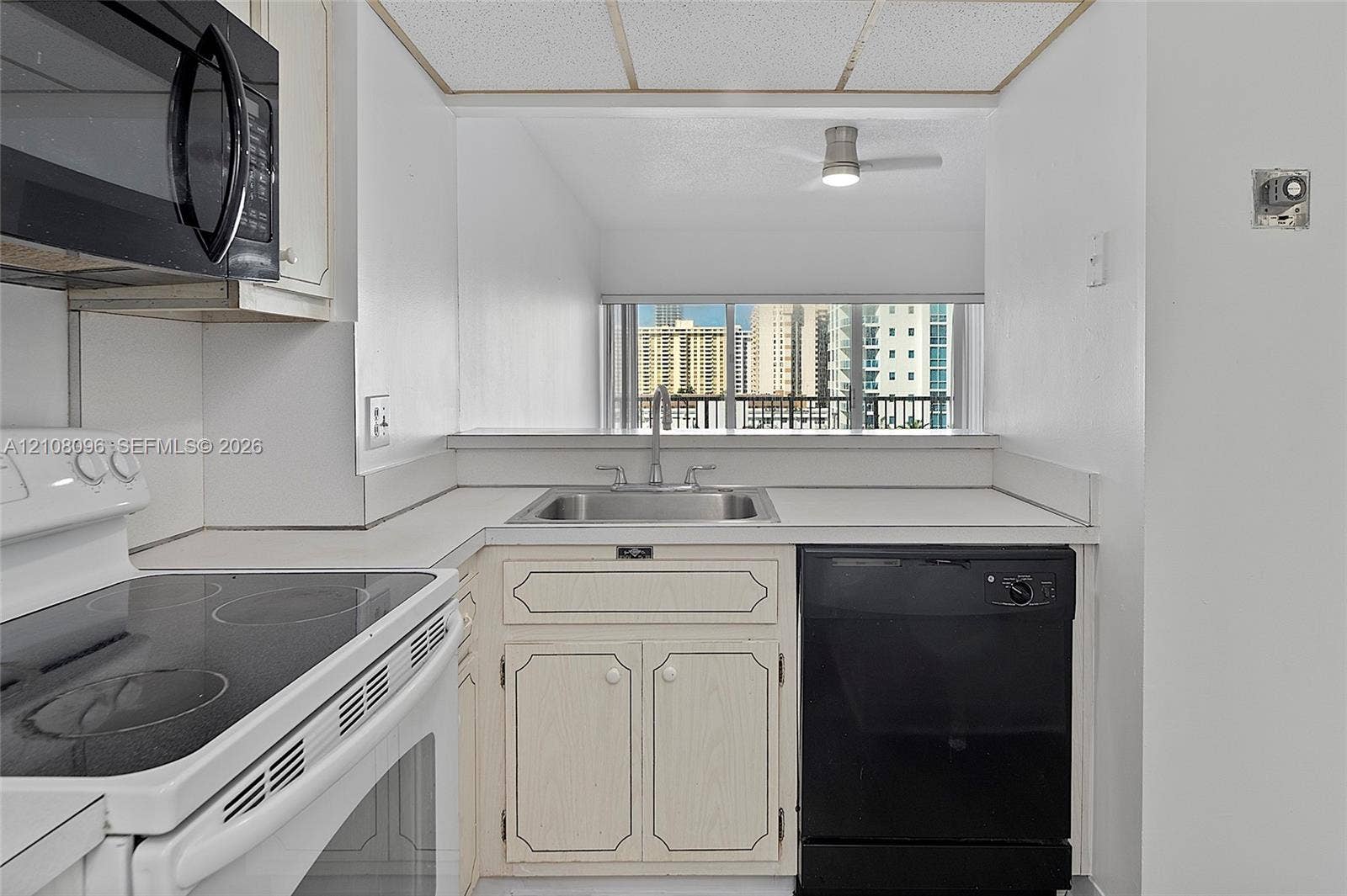 1965 S Ocean Drive, #6H, Hallandale Beach, Hallandale Beach, FL 33009 Kitchen featuring white cabinetry, integrated stainless steel sink with metal faucet, black dishwasher, and black over-the-range microwave