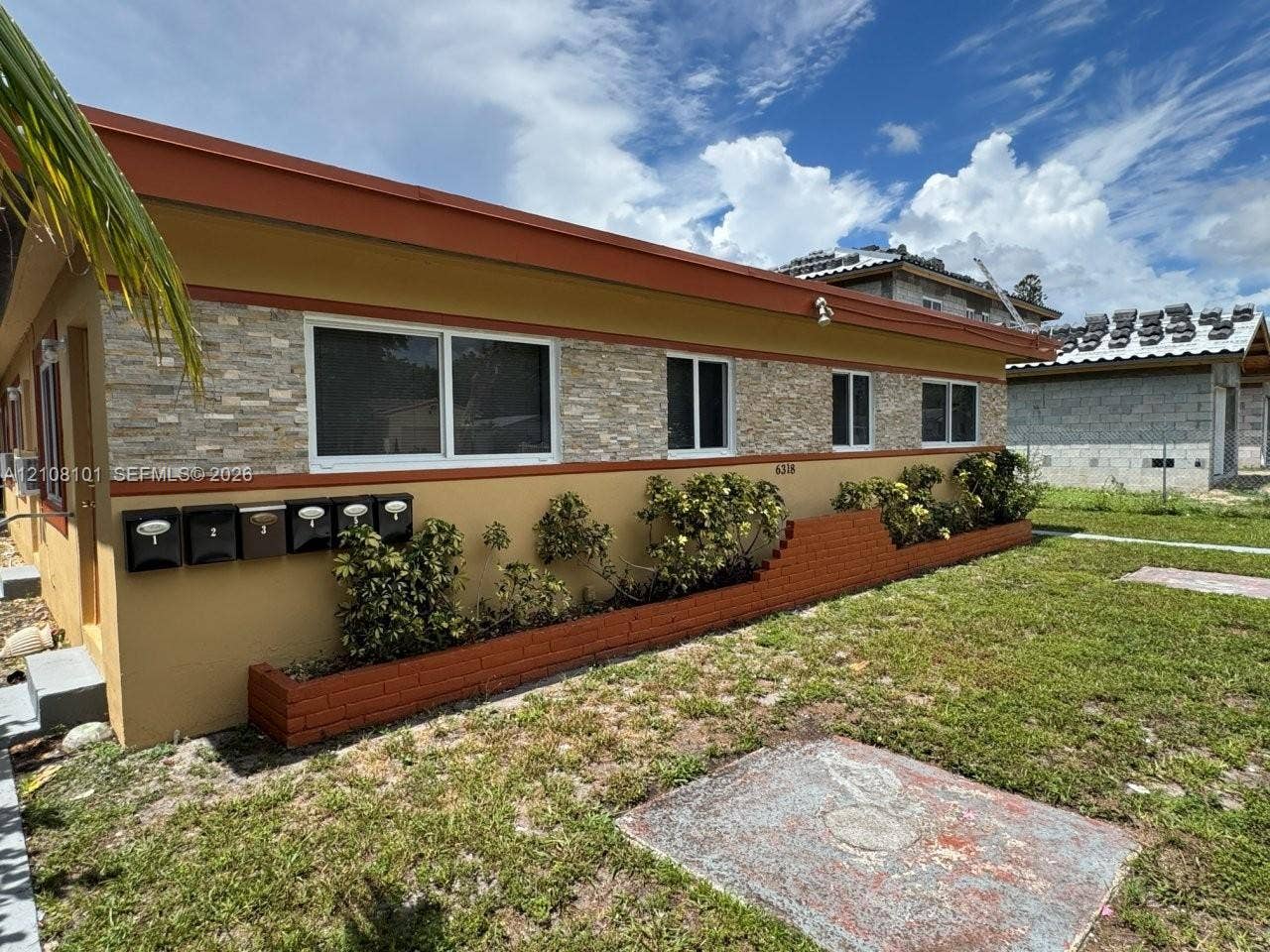 6318 Buchanan Street, #2, Hollywood, Hollywood, FL 33024 Exterior facade featuring multi-tone stucco finish, natural stacked stone veneer accents, integrated brick planter boxes, and a series of wall-mounted metal mailboxes