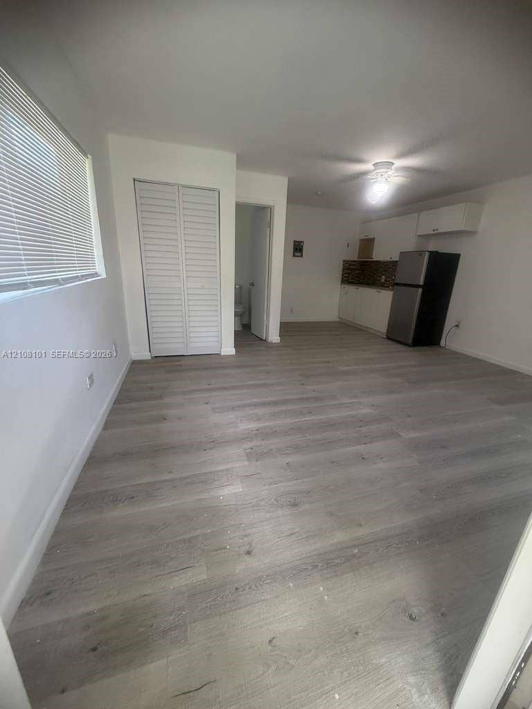 6318 Buchanan Street, #2, Hollywood, Hollywood, FL 33024 Open-concept space featuring wood-finish flooring, white cabinetry, a tiled backsplash, and louvered closet doors