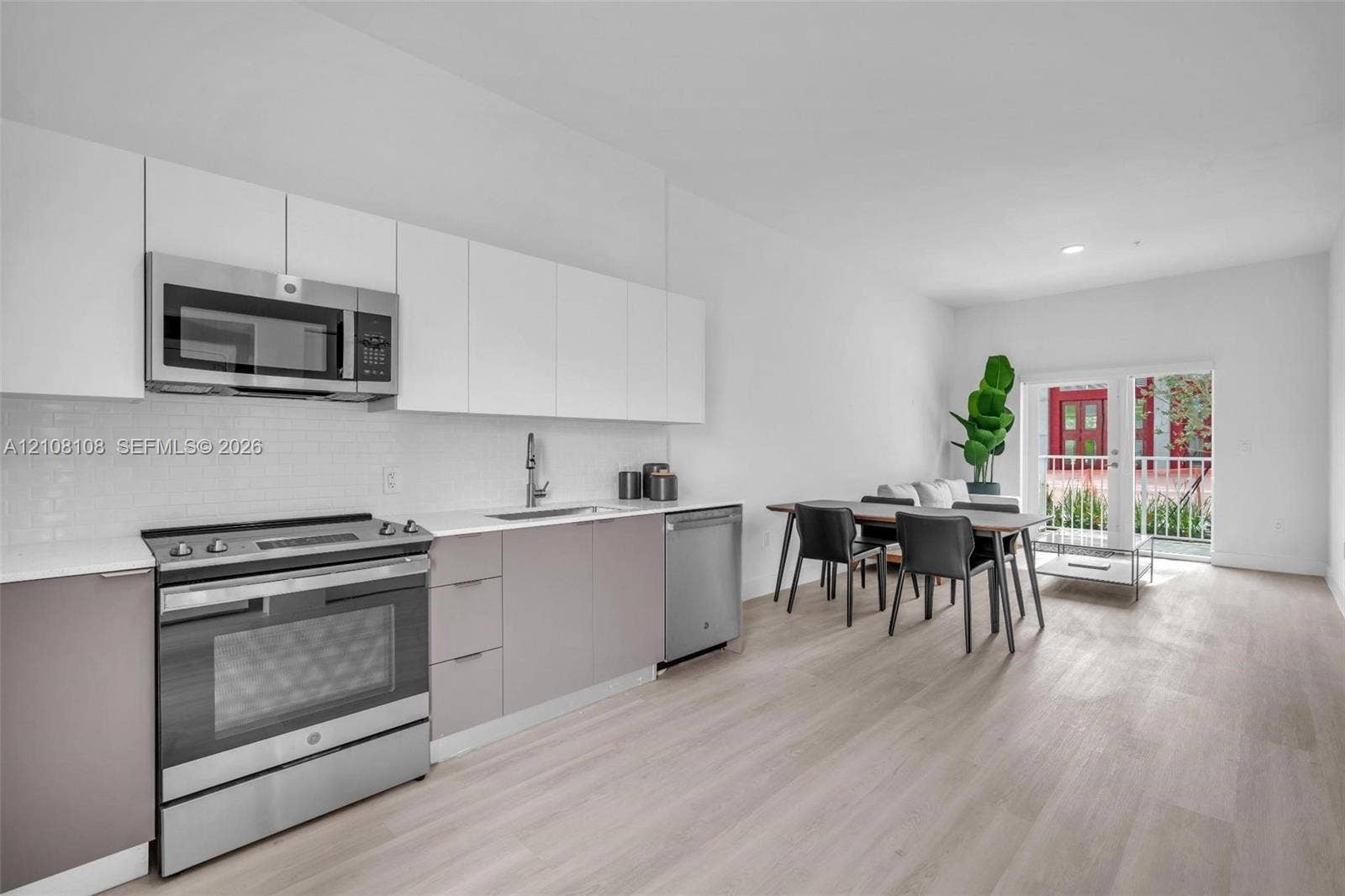 605 N Dixie Highway, #B207, Hallandale Beach, Hallandale Beach, FL 33009 Kitchen featuring two-tone flat-panel cabinetry, stainless steel appliances, white subway tile backsplash, quartz countertops, and wood-finish flooring