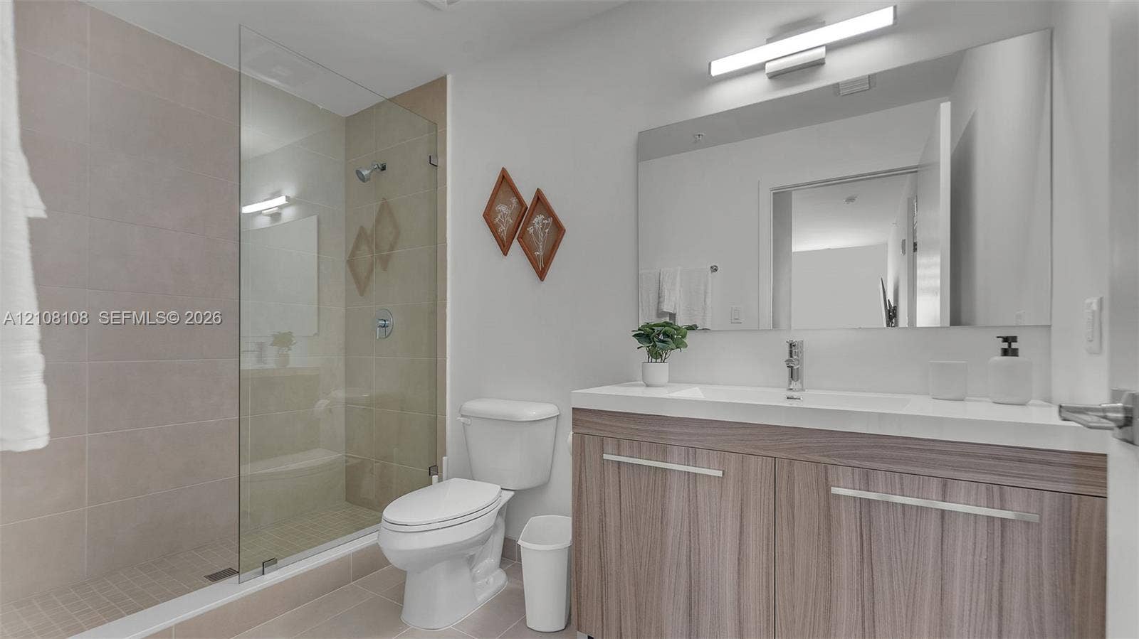 605 N Dixie Highway, #B207, Hallandale Beach, Hallandale Beach, FL 33009 Bathroom featuring a wood-finish vanity with a white countertop, a frameless glass shower enclosure, oversized wall-mounted mirror, and linear light fixture