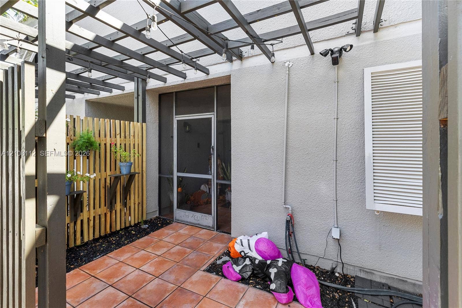 1431 NW 112th Terrace, Pembroke Pines, FL 33026 Outdoor patio featuring a wooden pergola, terracotta tile flooring, vertical slat wood privacy screen, and a screened entry door