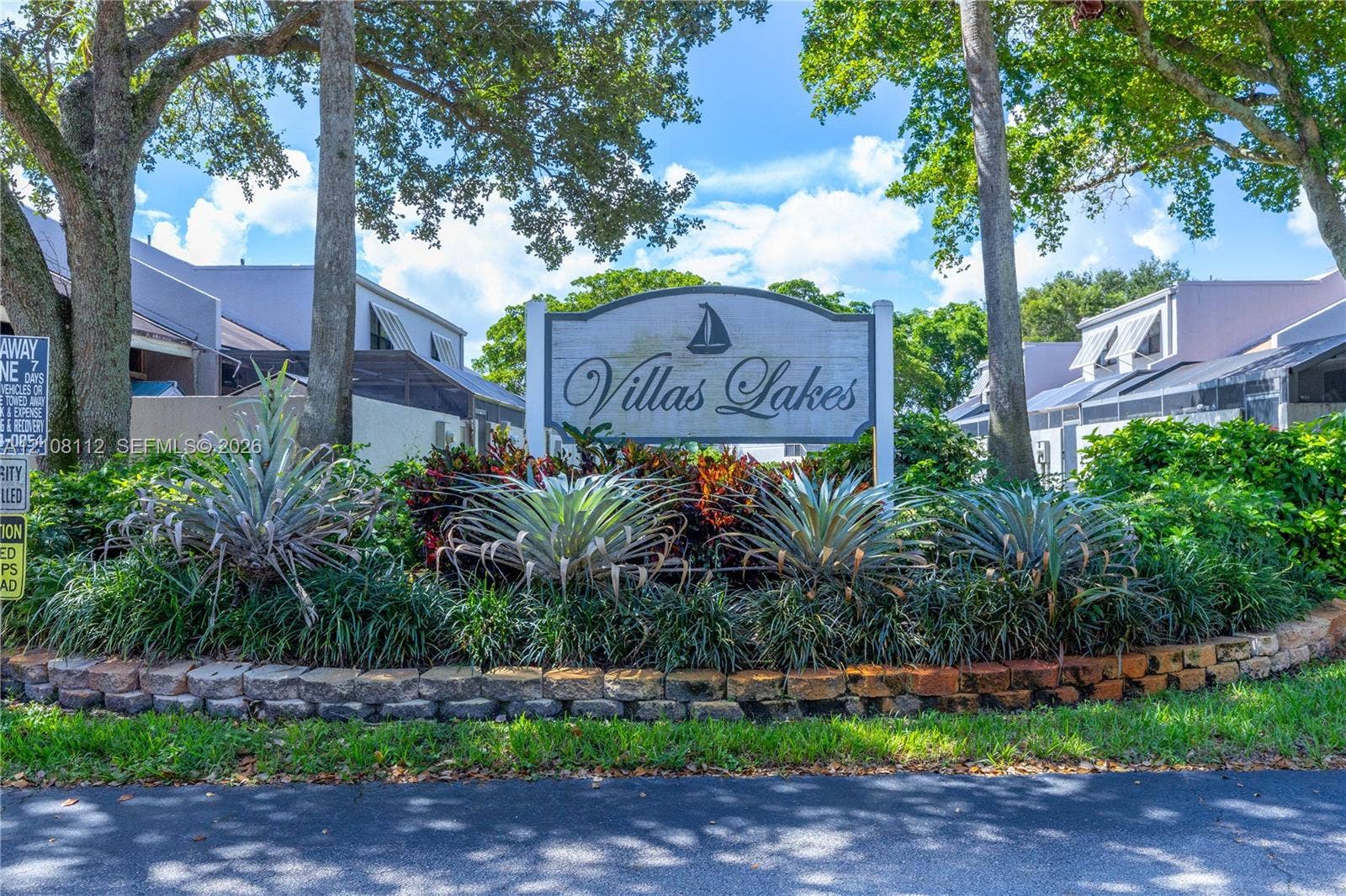 1431 NW 112th Terrace, Pembroke Pines, FL 33026 Community signage featuring mature canopy trees, sculpted landscaping, and a masonry border wall