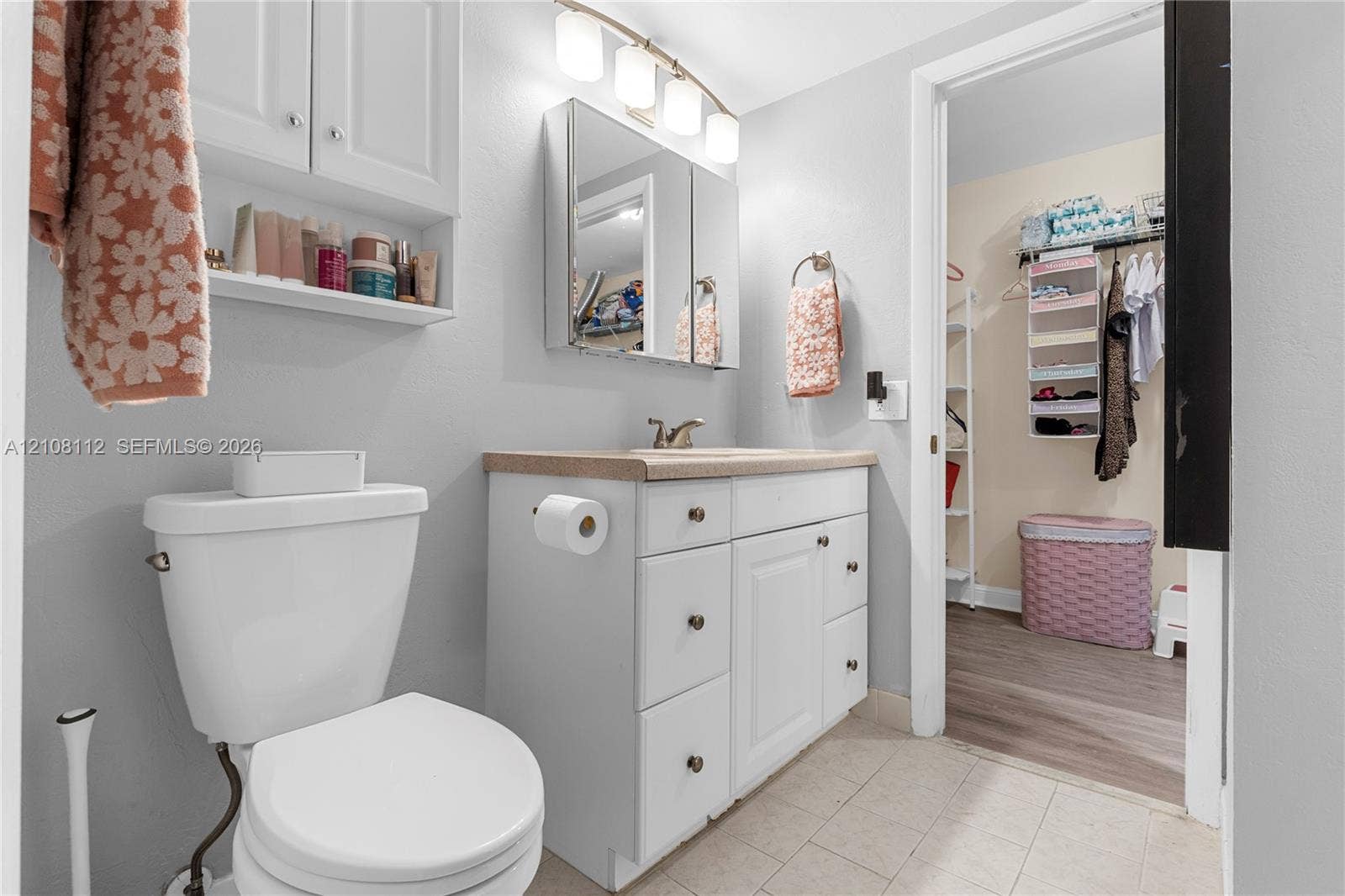 1431 NW 112th Terrace, Pembroke Pines, FL 33026 Bathroom featuring white cabinetry, a tri-panel medicine cabinet, wall-mounted light fixture, and solid surface countertop with an integrated sink