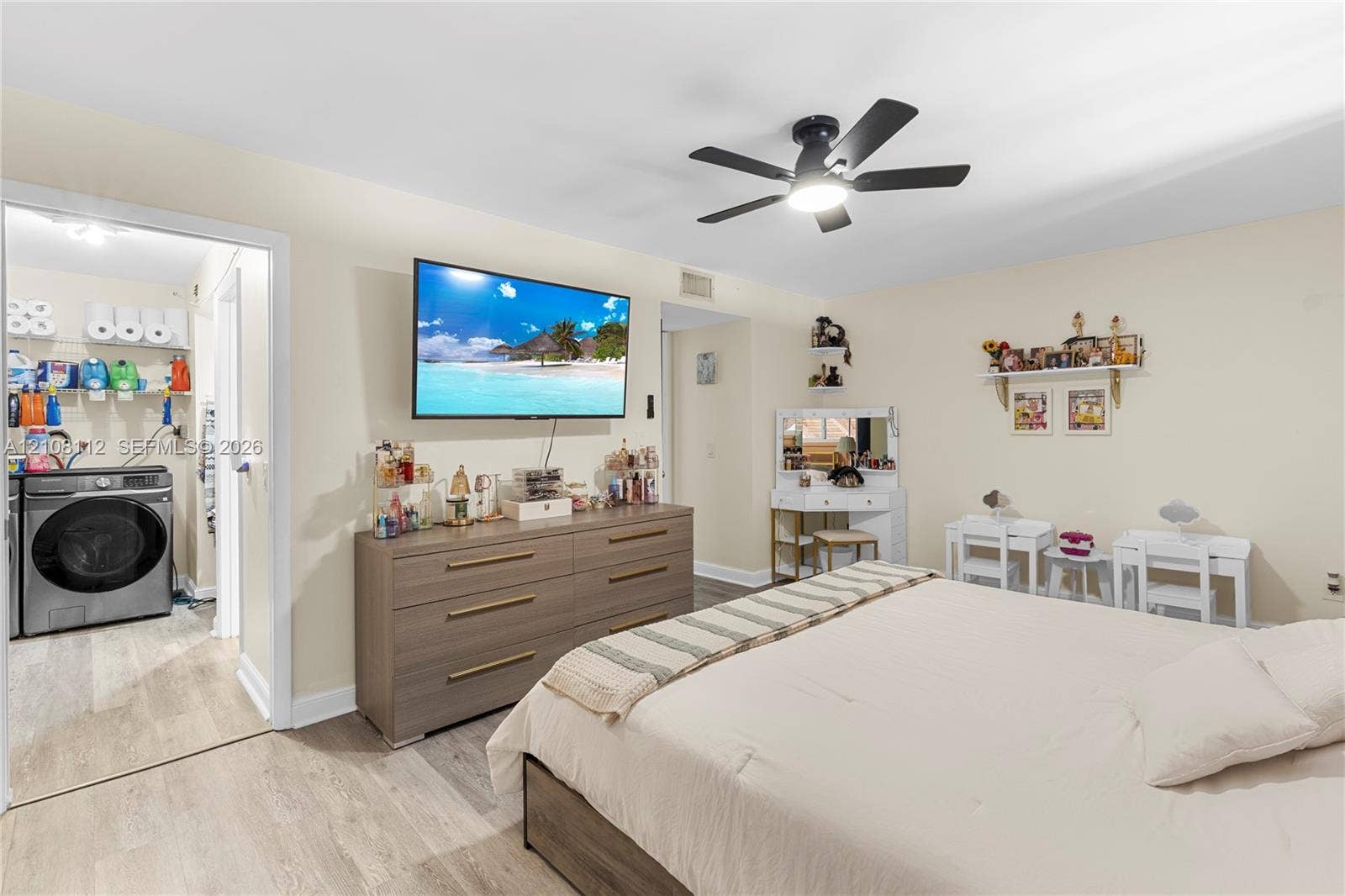 1431 NW 112th Terrace, Pembroke Pines, FL 33026 Neutral-toned room featuring wood-finish flooring, a ceiling fan with integrated lighting, and an attached laundry area with built-in shelving