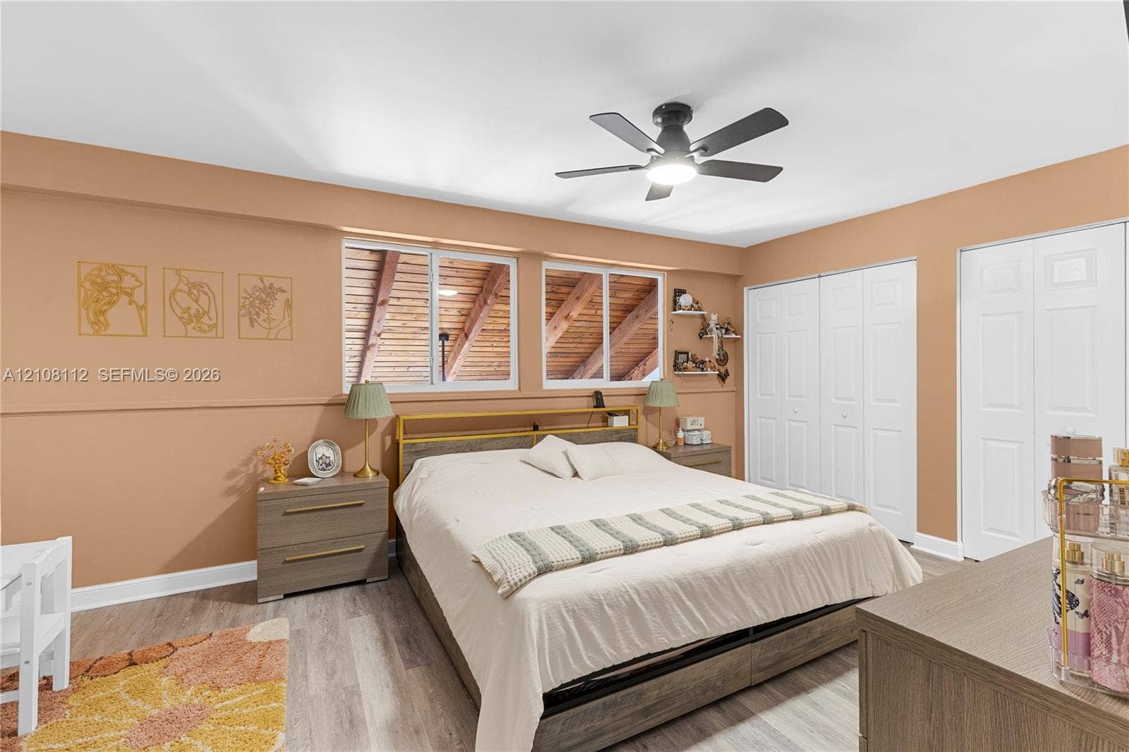 1431 NW 112th Terrace, Pembroke Pines, FL 33026 Bedroom featuring wood-finish flooring, dual windows with exposed wood rafters, ceiling fan with integrated lighting, and multiple bi-fold closets