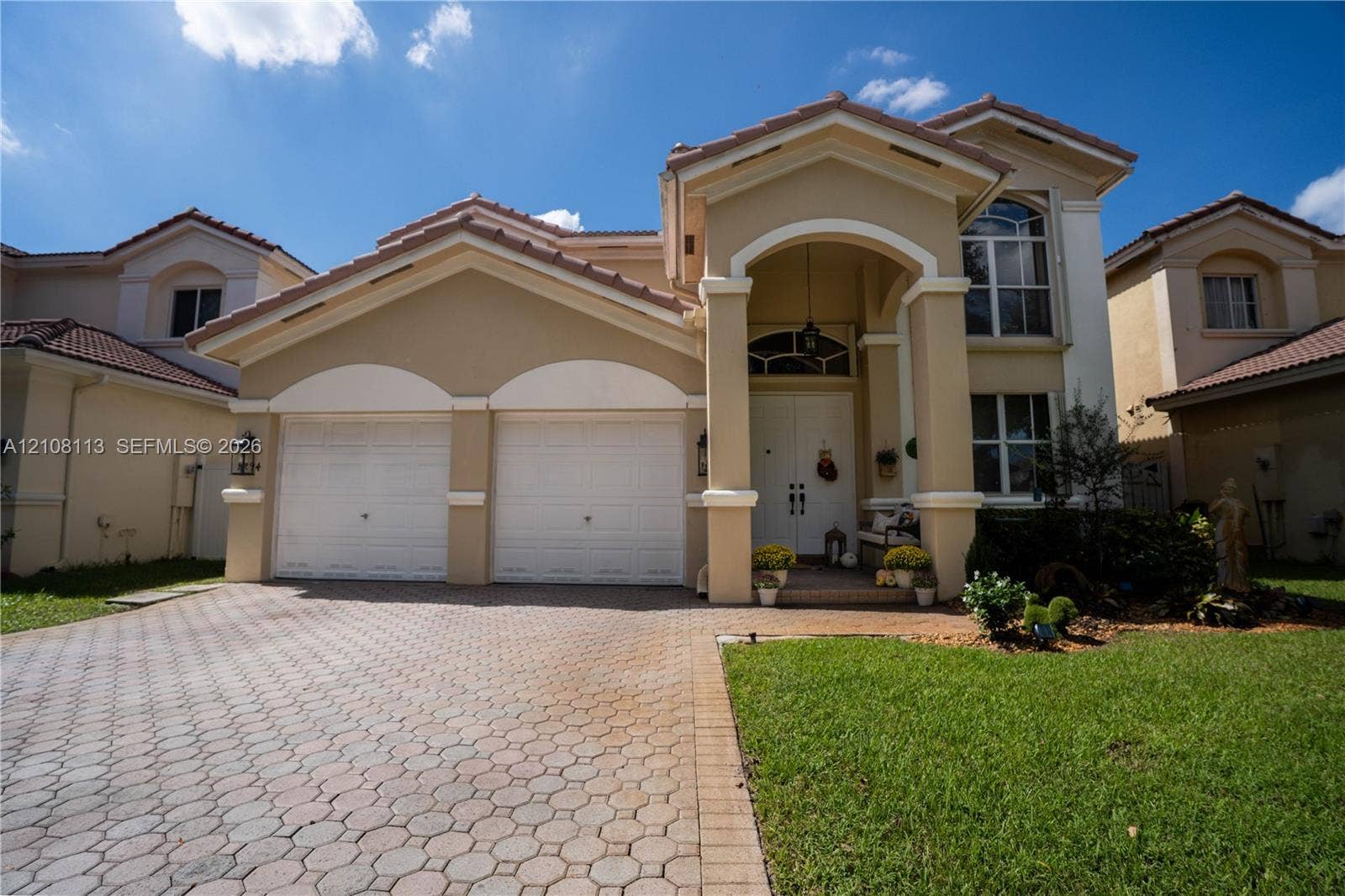 2294 SW 126th Avenue, Miramar, FL 33027 Two-story exterior featuring a stucco facade, tile roof, arched entryway with decorative columns, and a paved stone driveway leading to an attached two-car garage