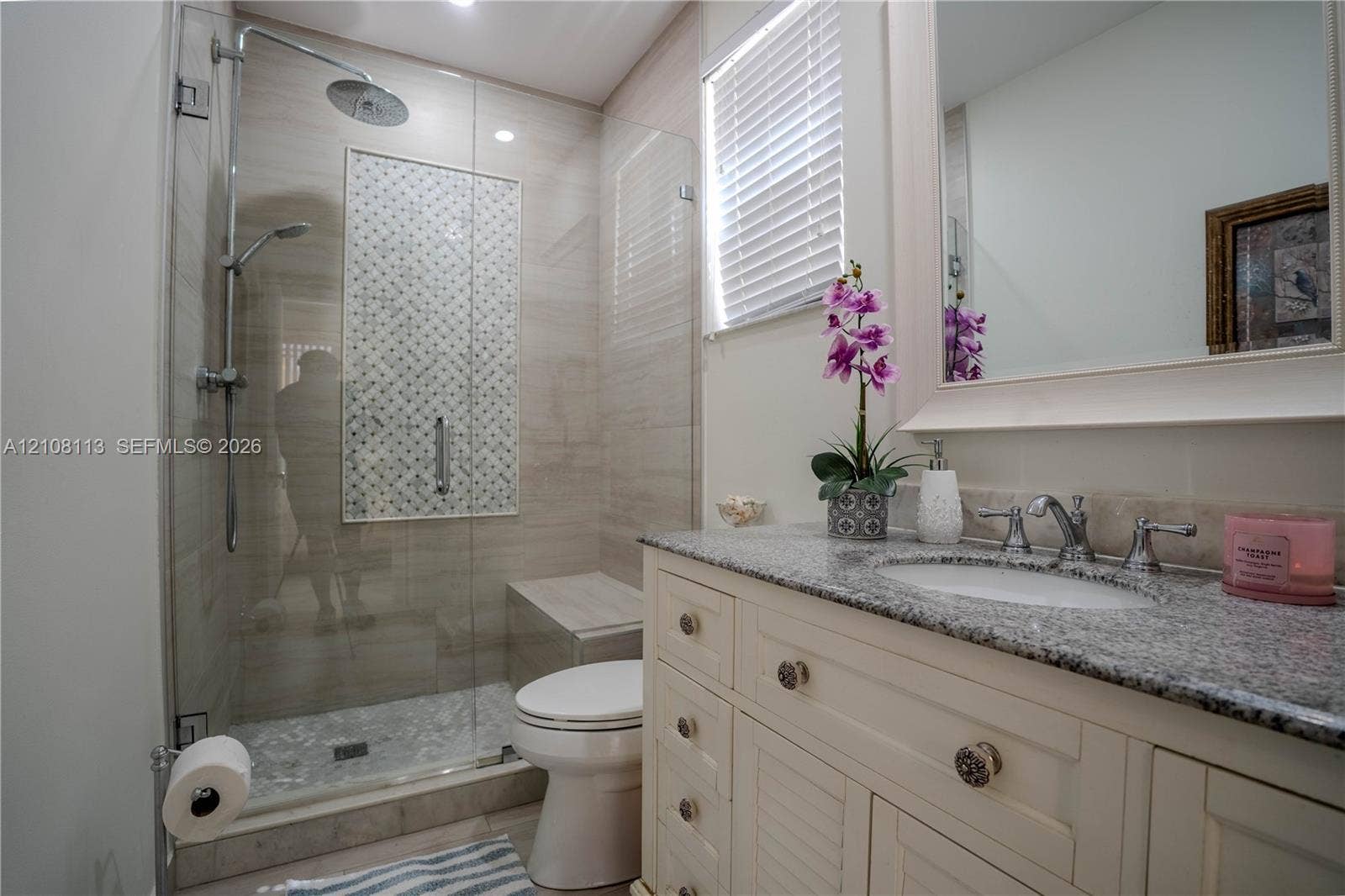 2294 SW 126th Avenue, Miramar, FL 33027 Bathroom featuring a vanity with stone-finish countertop, undermount sink, walk-in glass-enclosed shower with tiled accent inlay, and built-in shower bench