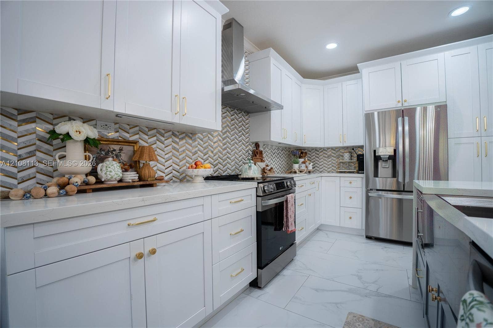 2294 SW 126th Avenue, Miramar, FL 33027 Kitchen featuring white shaker-style cabinetry, herringbone-patterned tile backsplash, stainless steel appliances, and large-format tile flooring