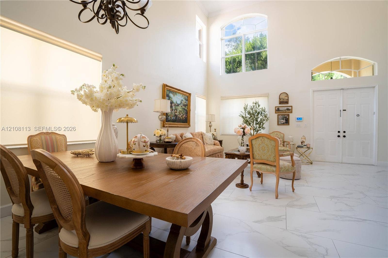 2294 SW 126th Avenue, Miramar, FL 33027 Open-concept interior featuring double-height ceilings, arched windows, large-format tile flooring, a decorative chandelier, and double-door entry