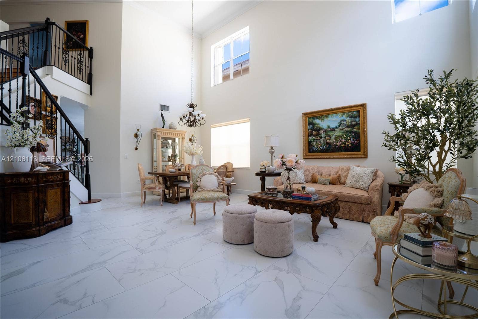 2294 SW 126th Avenue, Miramar, FL 33027 Two-story ceiling height, large-format tile flooring with marble-finish veining, grand staircase with wrought-iron balusters, multi-level windows, and a central tiered chandelier
