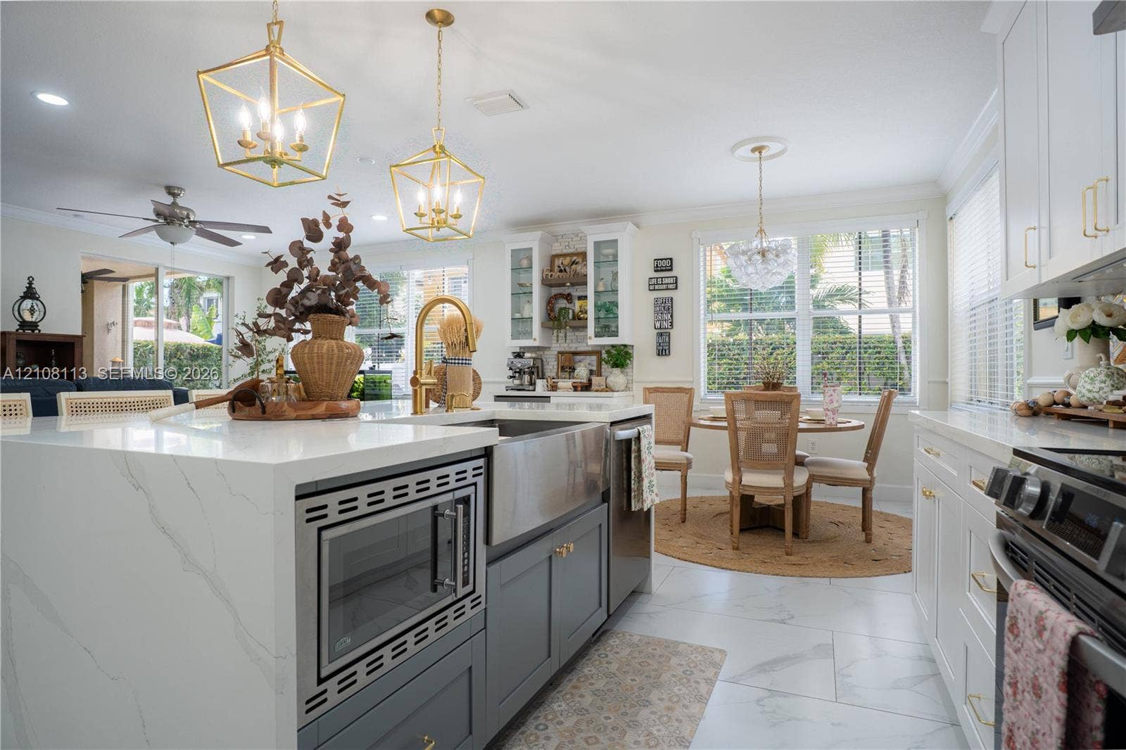 2294 SW 126th Avenue, Miramar, FL 33027 Kitchen featuring a central island with a waterfall-edge countertop, farmhouse sink, brass-finish hardware, geometric pendant lighting, and light-toned tile flooring