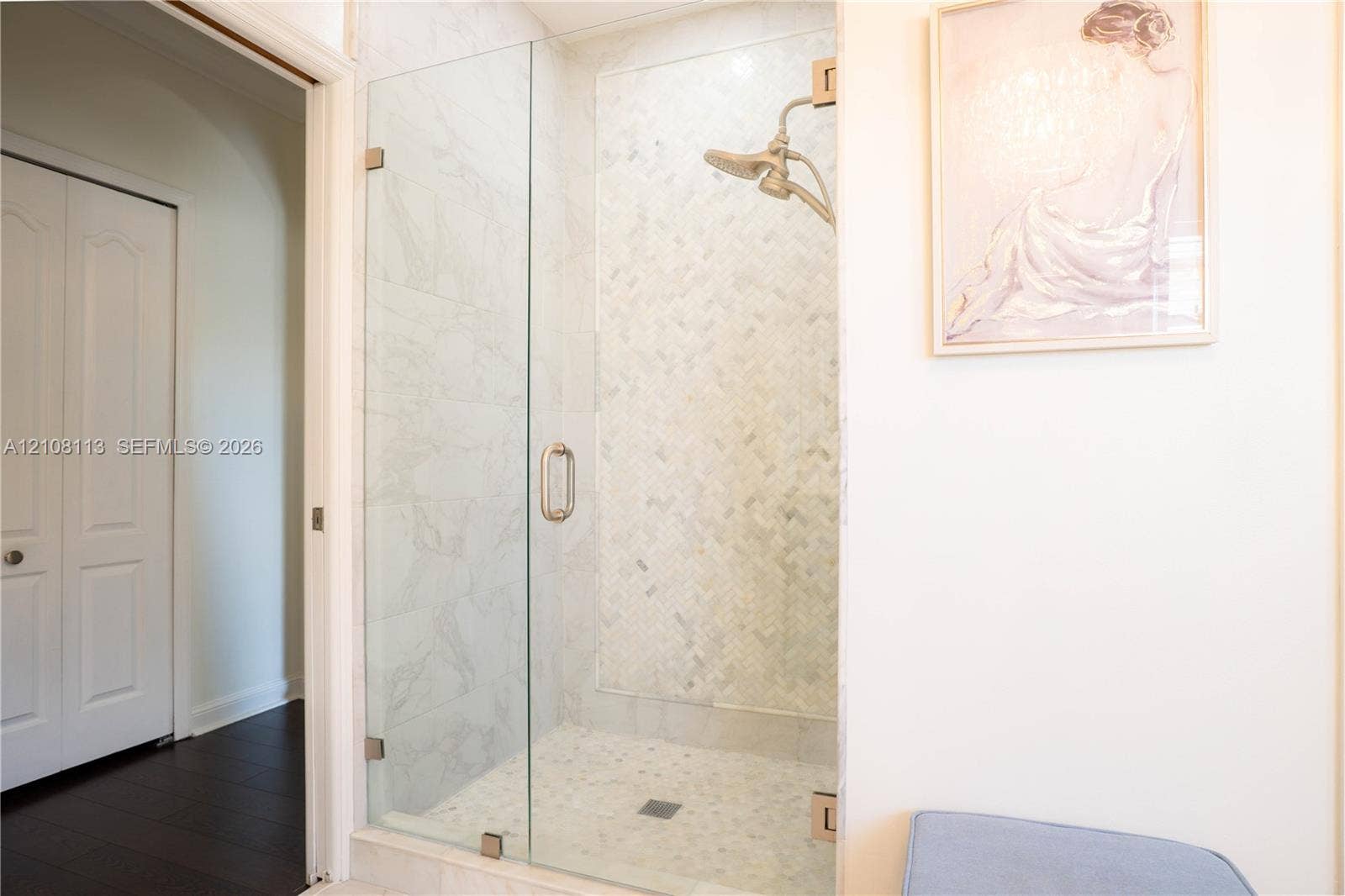 2294 SW 126th Avenue, Miramar, FL 33027 Walk-in shower featuring a frameless glass door, herringbone-patterned stone tile surround, pebble-style stone flooring, and a metallic finish shower head