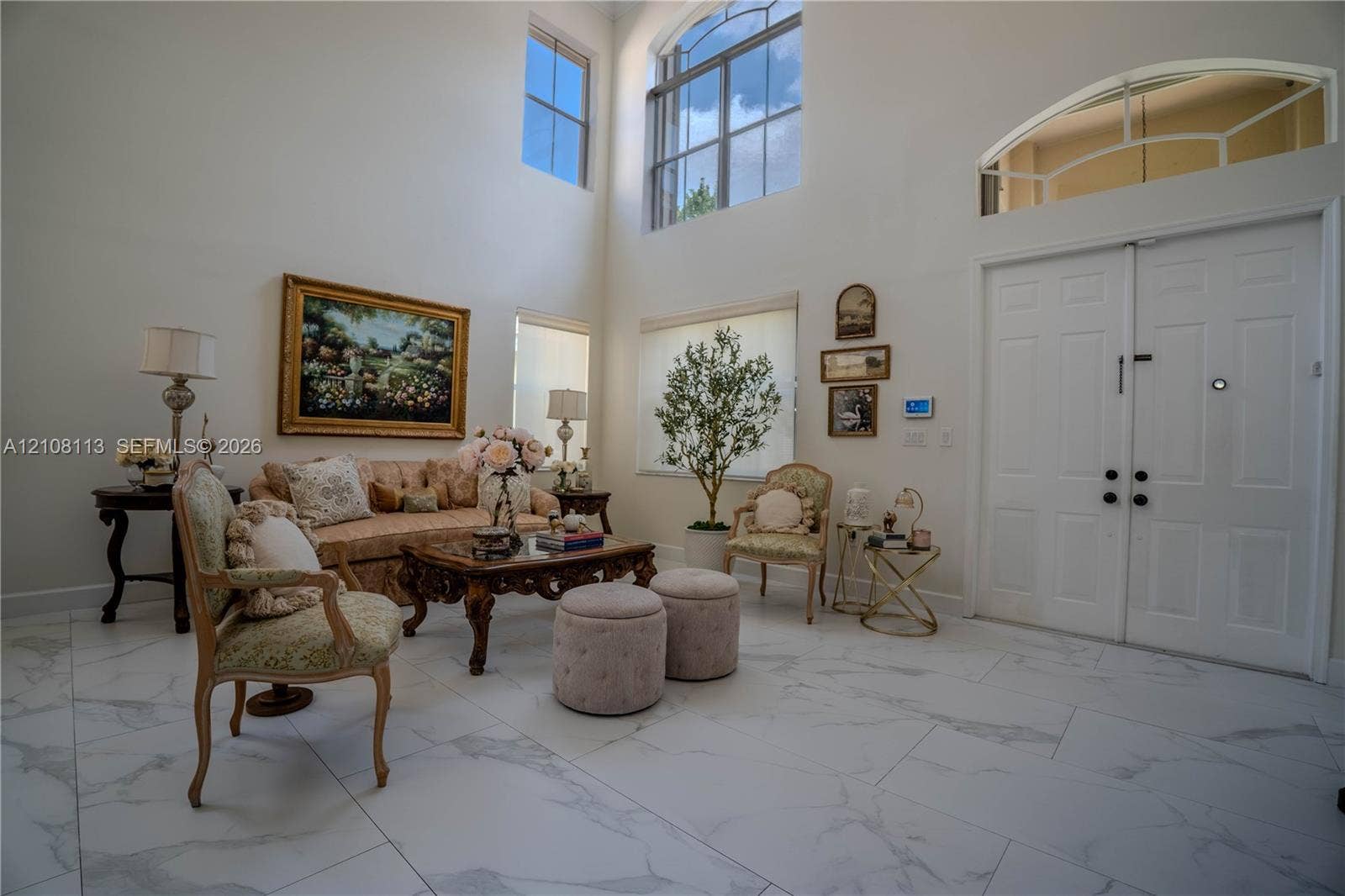 2294 SW 126th Avenue, Miramar, FL 33027 Double-height ceilings featuring expansive windows with an arched transom, double-door entry, and large-format tile flooring with marble-pattern veining
