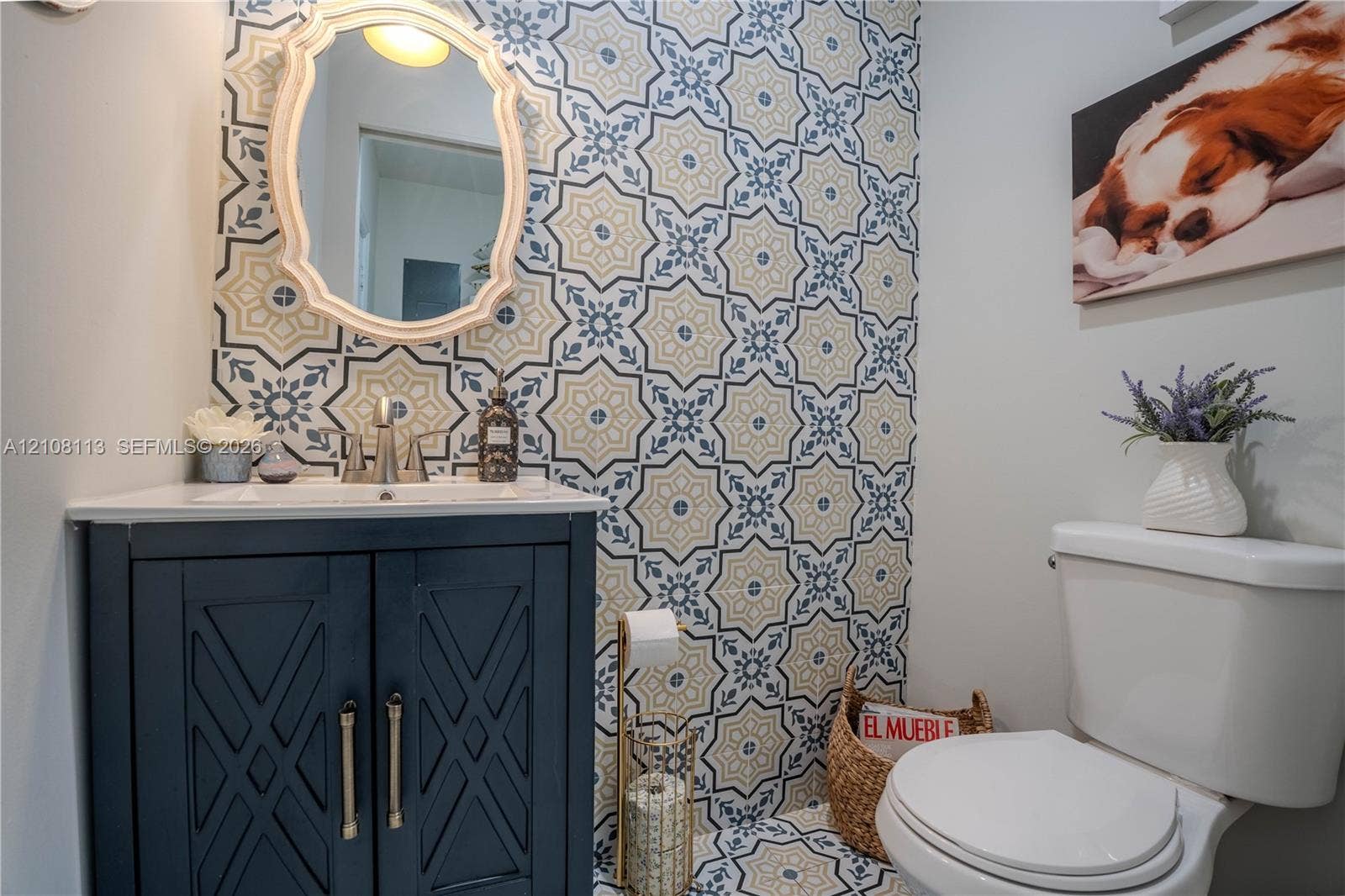 2294 SW 126th Avenue, Miramar, FL 33027 Powder room featuring geometric patterned tile wall and floor accents, navy blue built-in vanity, white countertop with integrated sink, and an arched wall-mounted mirror