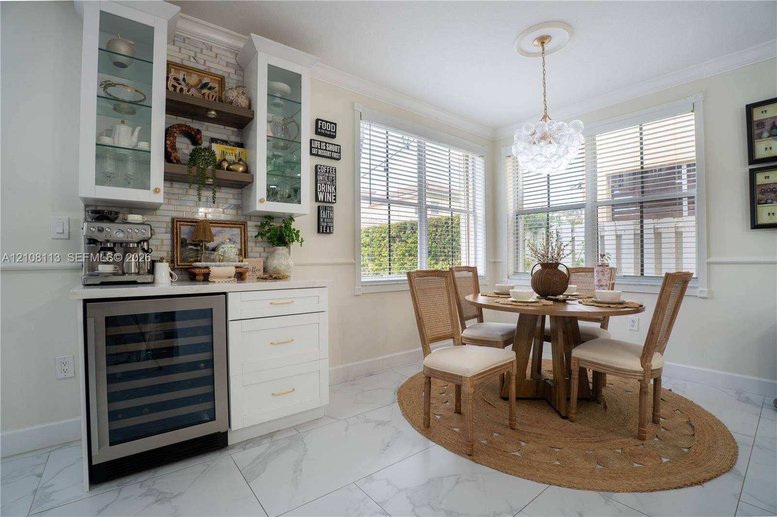 2294 SW 126th Avenue, Miramar, FL 33027 Breakfast area featuring white cabinetry with glass-front uppers, built-in wine refrigerator, white subway tile backsplash, crown molding, and large windows with horizontal blinds