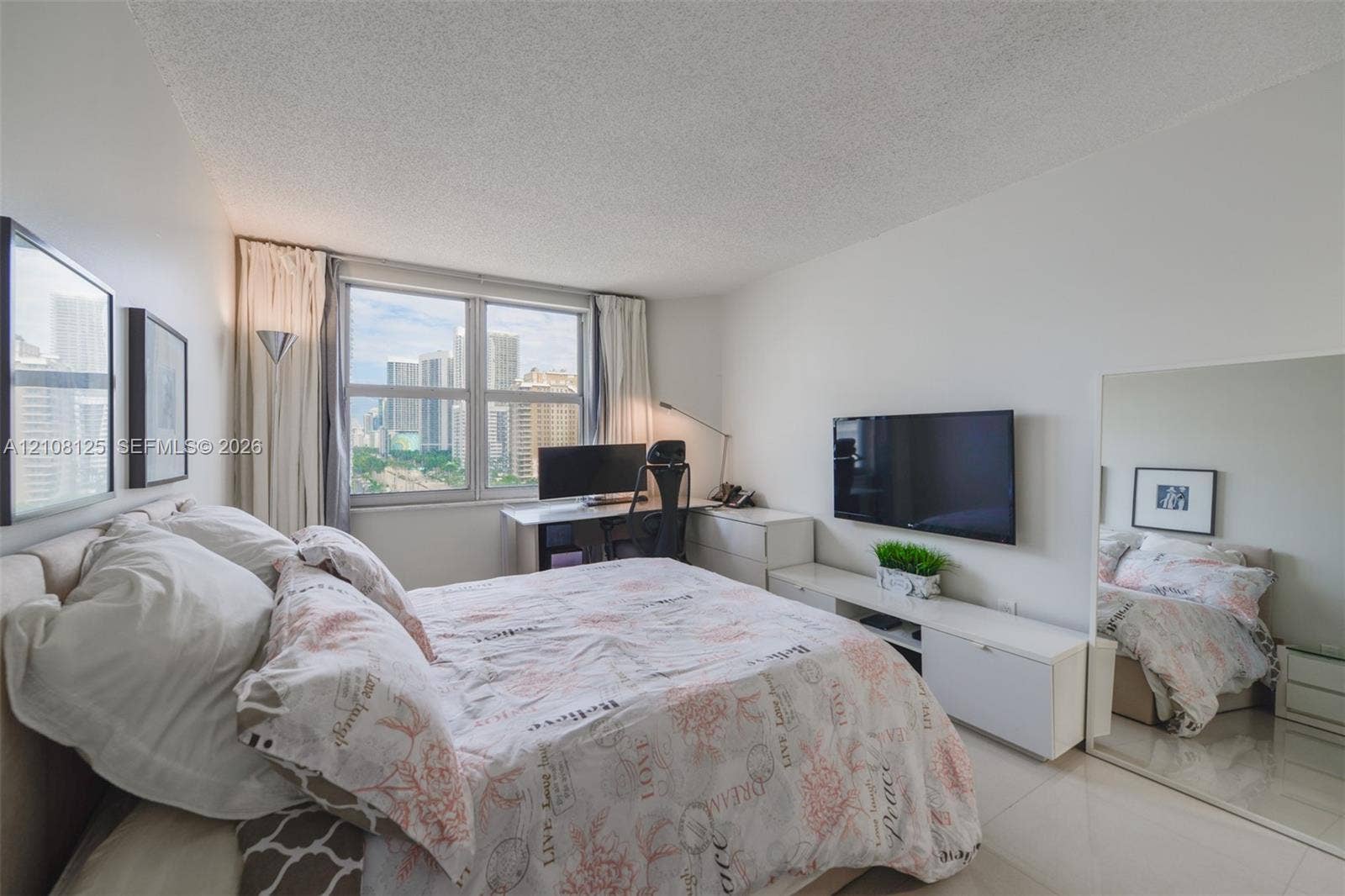 1985 S Ocean Drive, #8M, Hallandale Beach, FL 33009 Bright room featuring large-format tile flooring, textured ceiling, expansive window, and integrated mirrored wall panel
