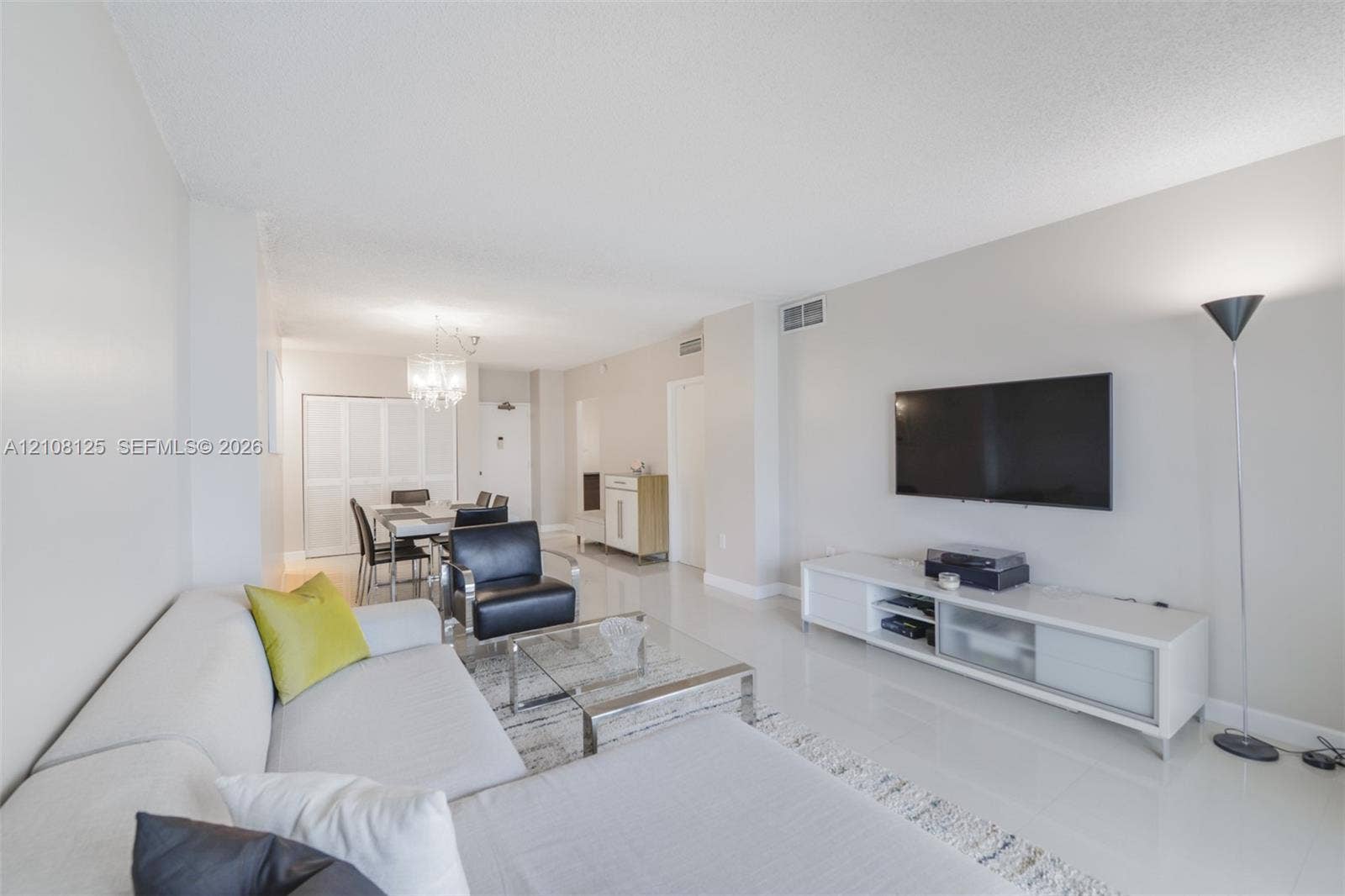 1985 S Ocean Drive, #8M, Hallandale Beach, FL 33009 Open-concept living space featuring high-gloss tile flooring, neutral wall tones, and a crystal chandelier