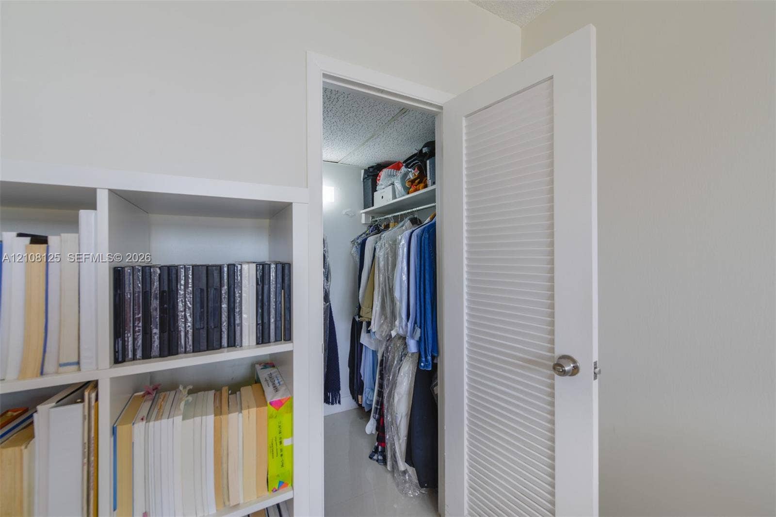 1985 S Ocean Drive, #8M, Hallandale Beach, FL 33009 White louvered door providing entry to a storage space featuring a built-in overhead shelf and hanging rod