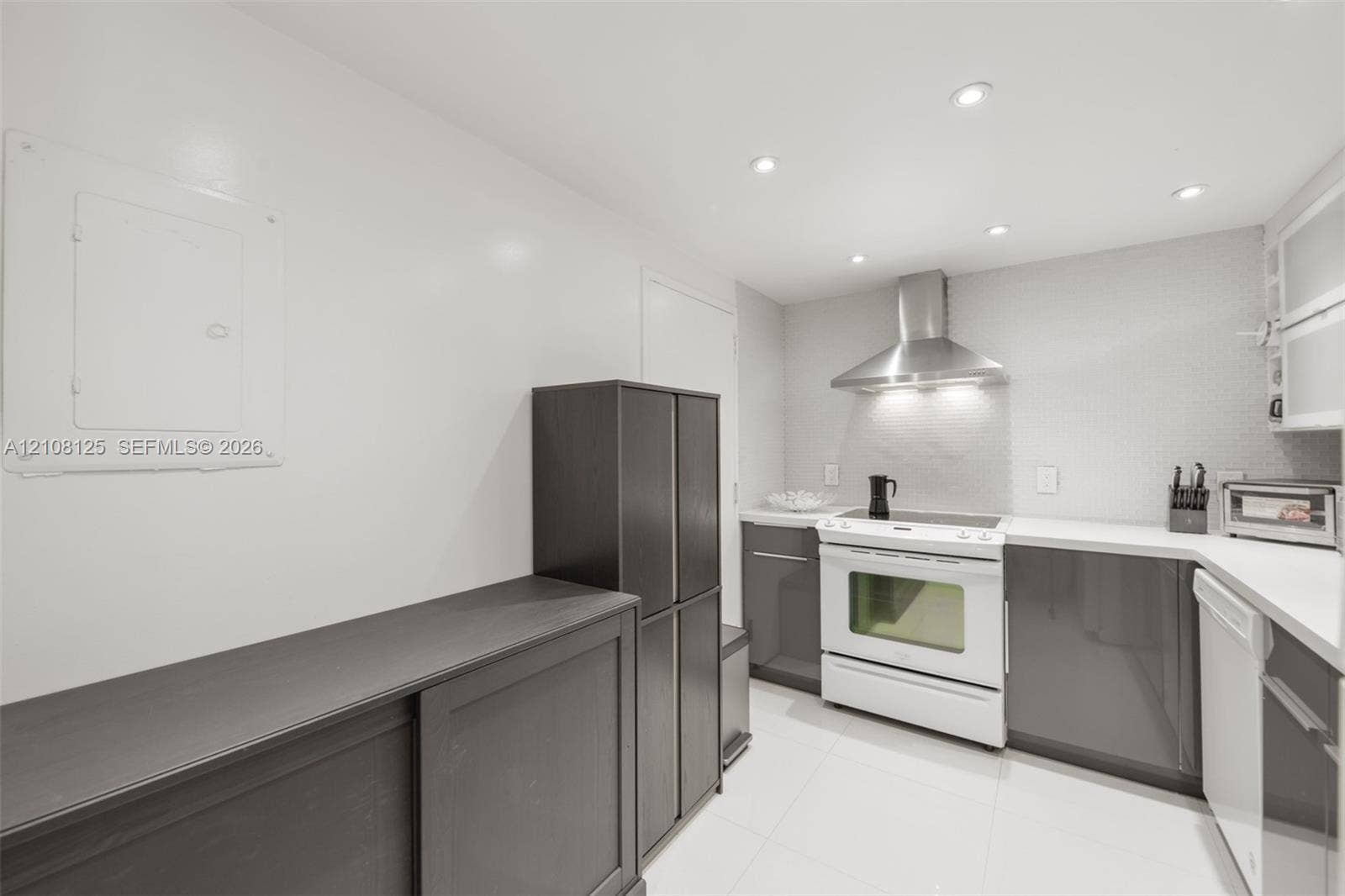 1985 S Ocean Drive, #8M, Hallandale Beach, FL 33009 Kitchen featuring dark-toned cabinetry, white countertops, stainless steel range hood, built-in range, and recessed ceiling lighting