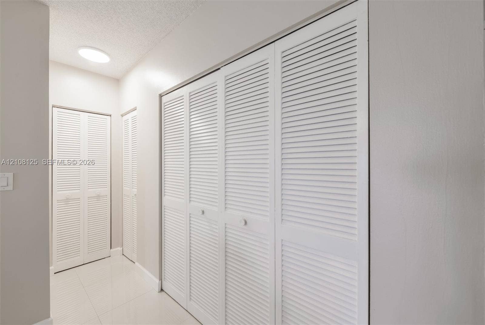 1985 S Ocean Drive, #8M, Hallandale Beach, FL 33009 White louvered closet doors, neutral wall finish, and tile flooring