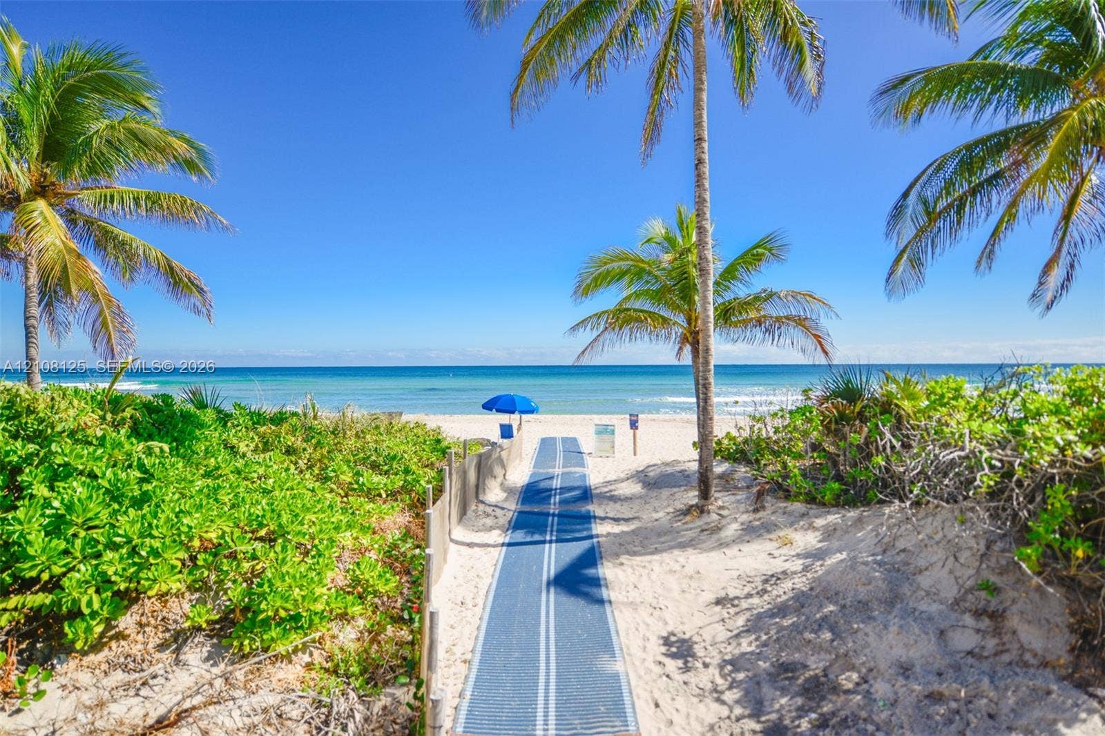 1985 S Ocean Drive, #8M, Hallandale Beach, FL 33009 Private sandy beach access featuring a synthetic pathway, native coastal vegetation, and palm trees